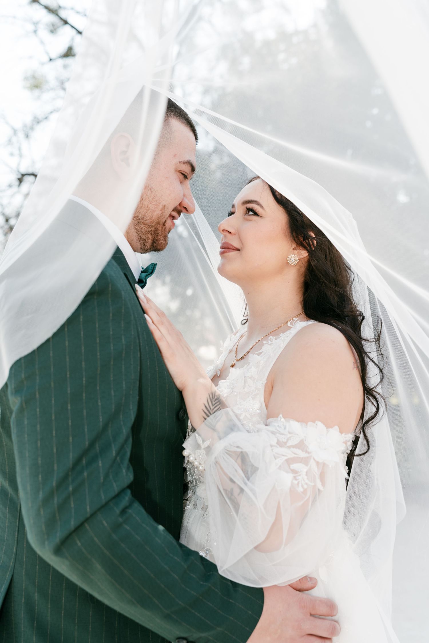Romantic bride and groom nearly kissing under a flowing white veil in a soft dreamy outdoor setting. Mallorca wedding photographer, filmmake