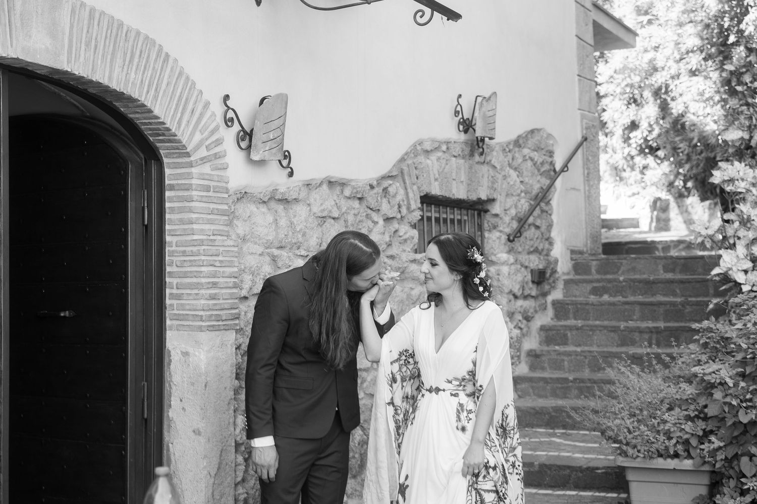 Black and white photo of a bride and groom sharing a tender moment outside a rustic stone building. Tuscany wedding photographer, filmmaker