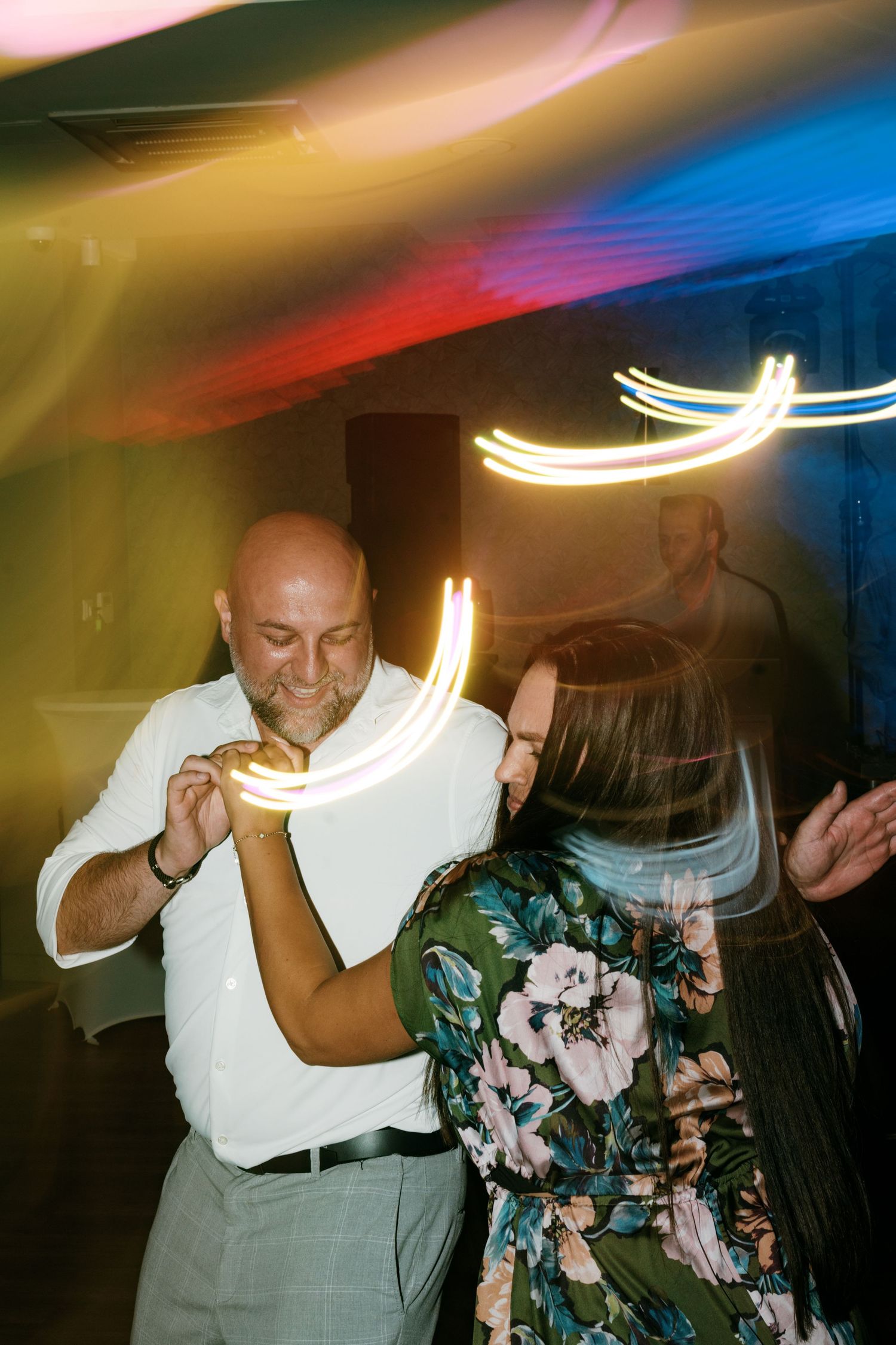 Couple dancing closely at wedding reception with colorful light trails. Italy wedding photographer and filmmaker