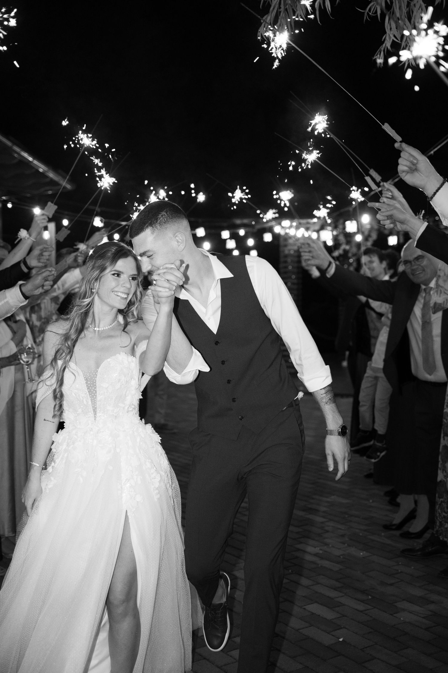 Black and white photo of bride and groom exiting through sparkler tunnel at night. Mallorca wedding photographer and filmmaker.