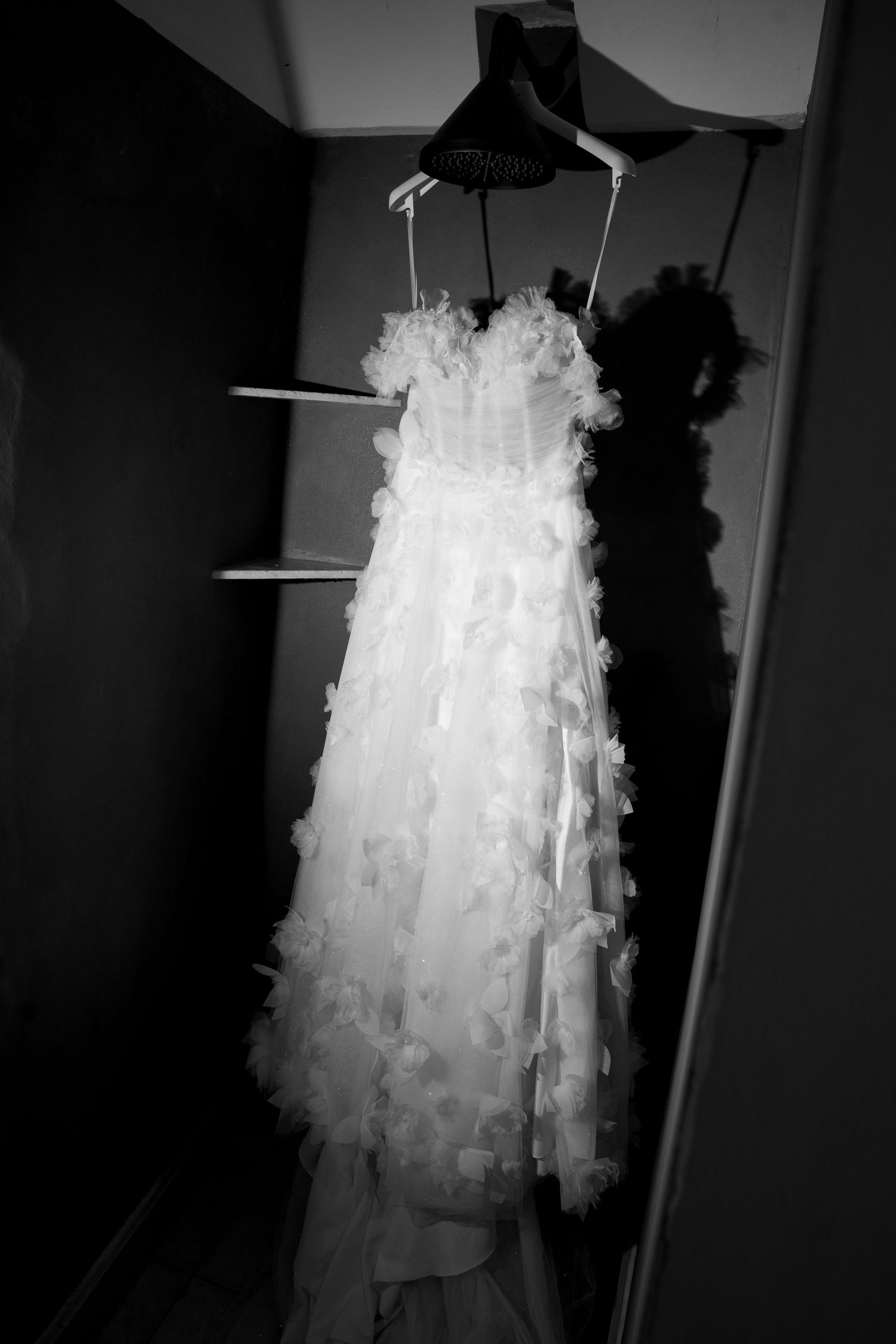 Black and white photo of an elegant floral applique wedding dress hanging in a closet on a hanger. Mallorca wedding photographer, filmmaker