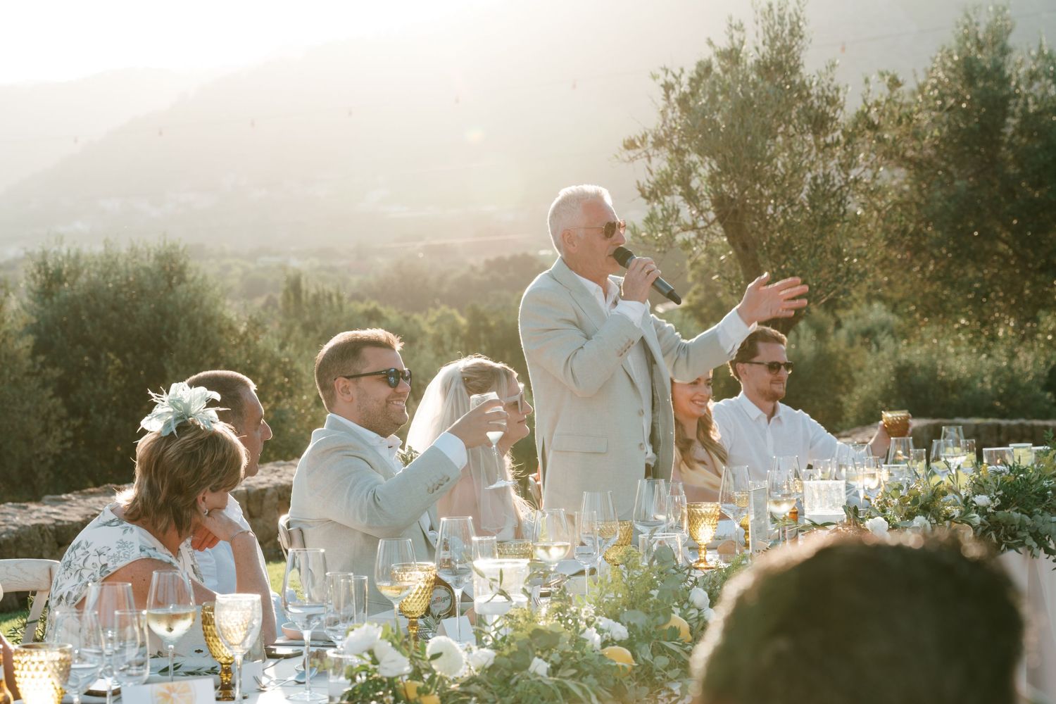 Man gives a heartfelt wedding speech at an outdoor reception with mountain views at golden hour. Tuscany wedding photographer, filmmaker