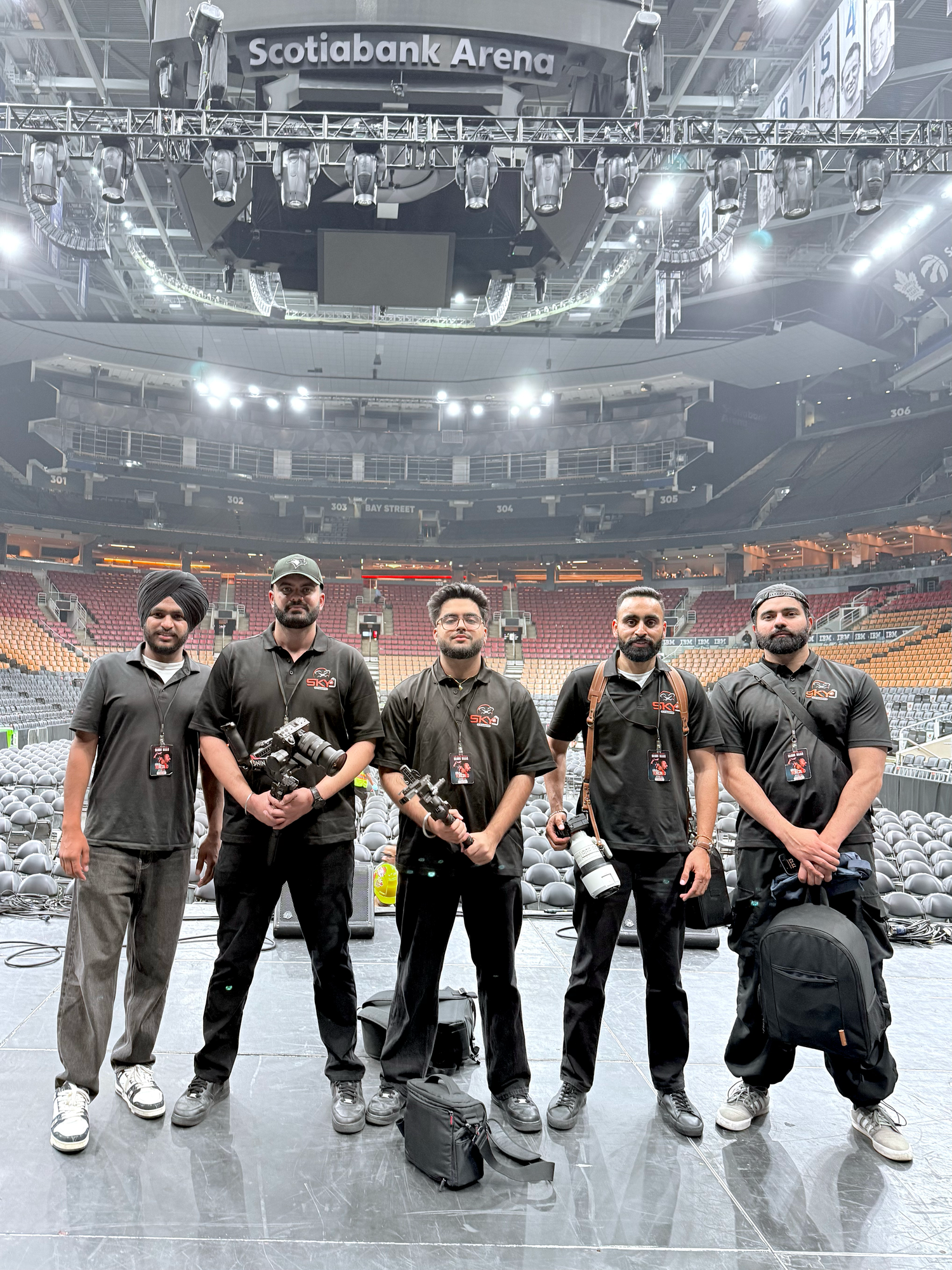 Five professional videographers and photographers posing with equipment inside Scotiabank Arena.