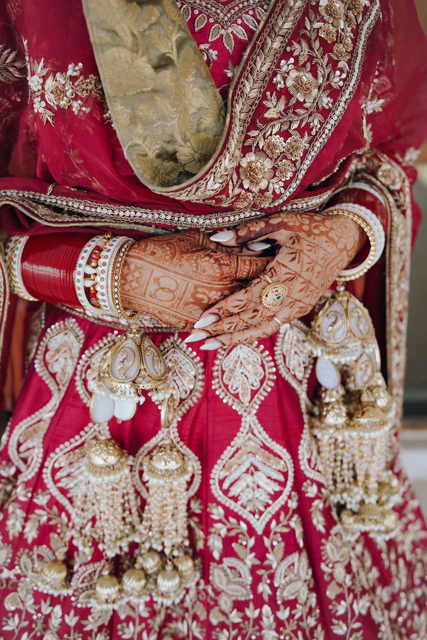 Close-up of Indian bride hands adorned with henna mehndi holding decorative kalire wedding accessories.