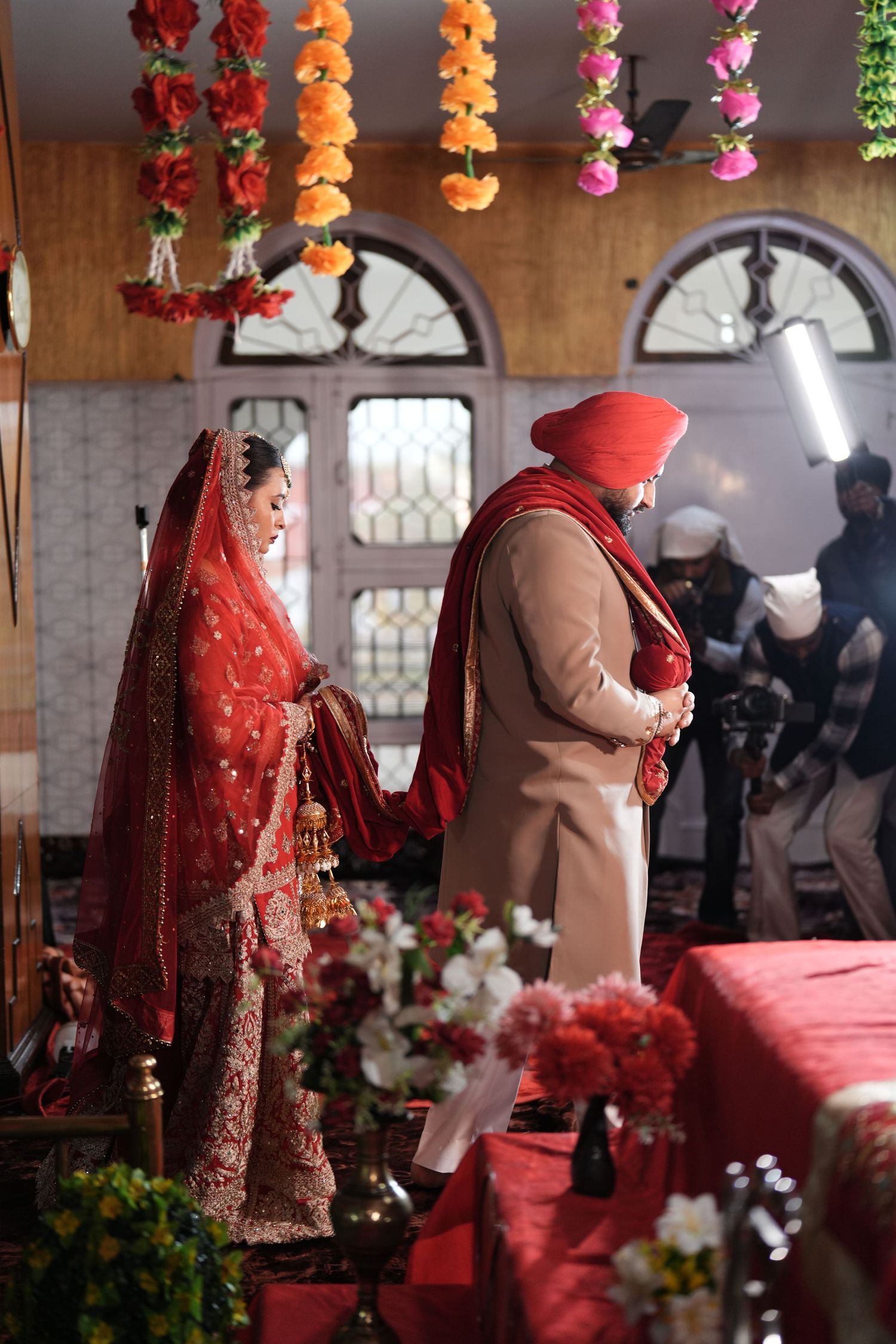 Sikh bride and groom performing Anand Karaj ceremony in decorated Gurudwara.