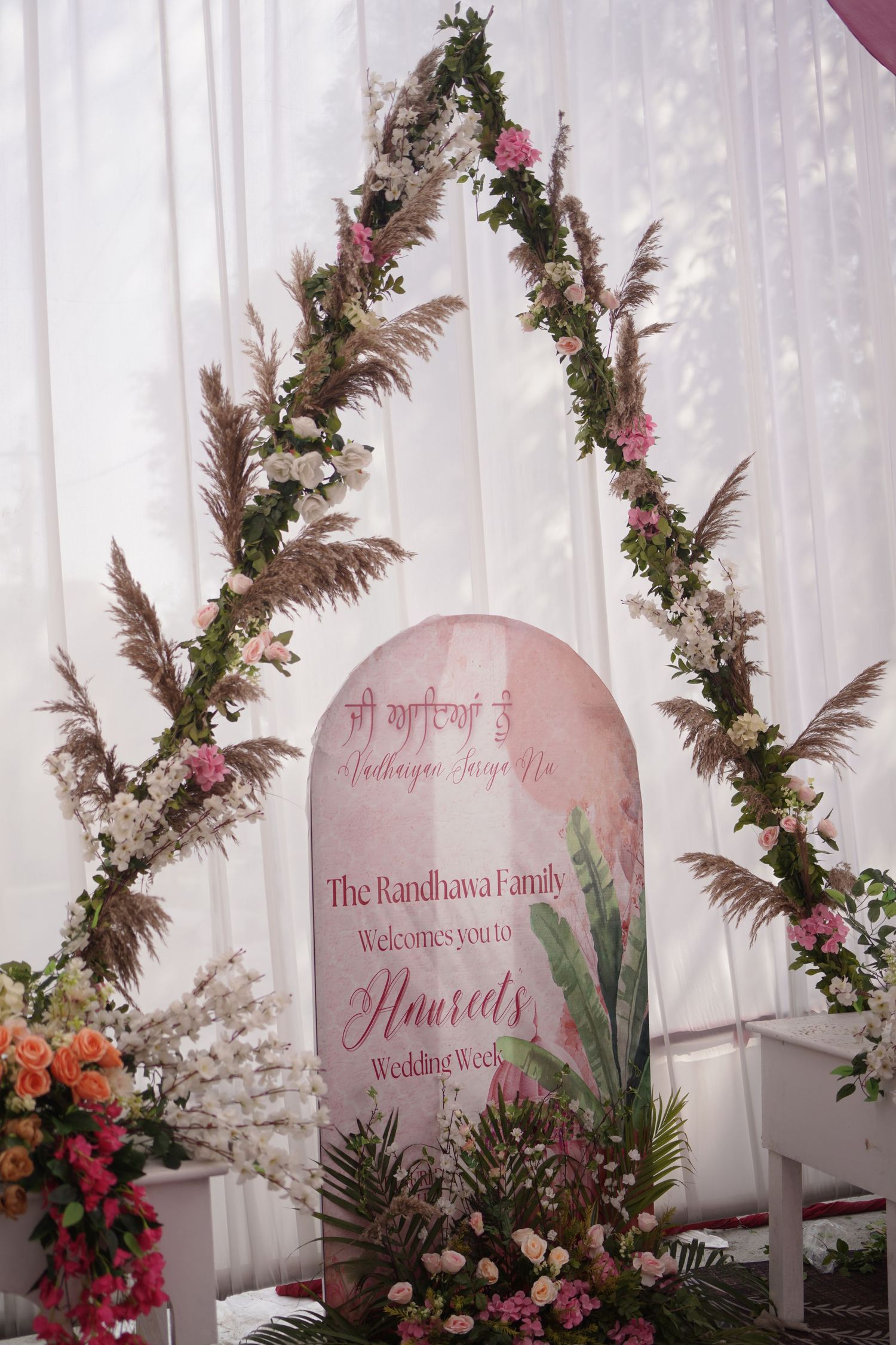 Floral wedding welcome sign for Randhawa family with pampas grass arch decor.