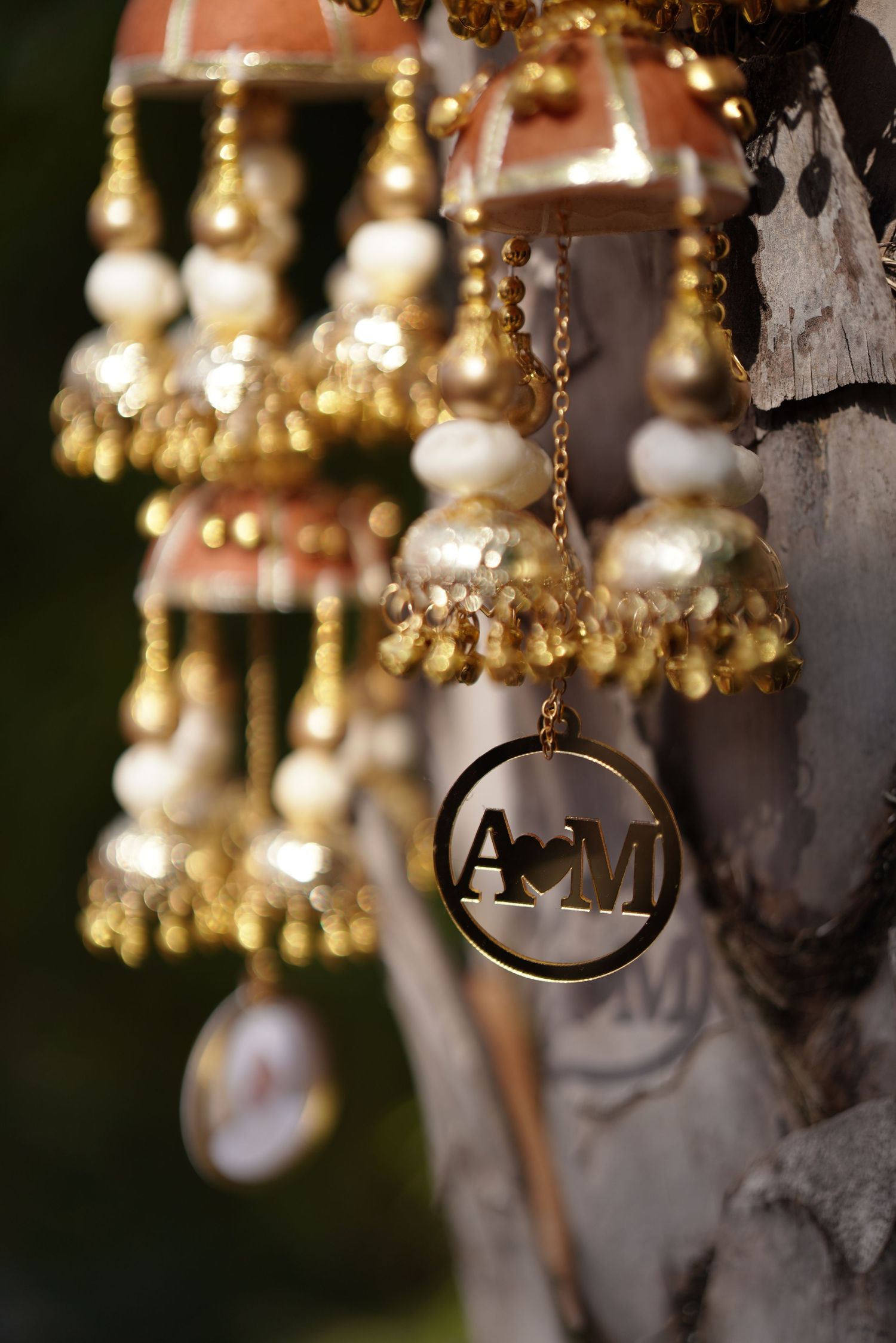 Gold jhumka earrings with pearl details and personalized A&M monogram charm pendant.