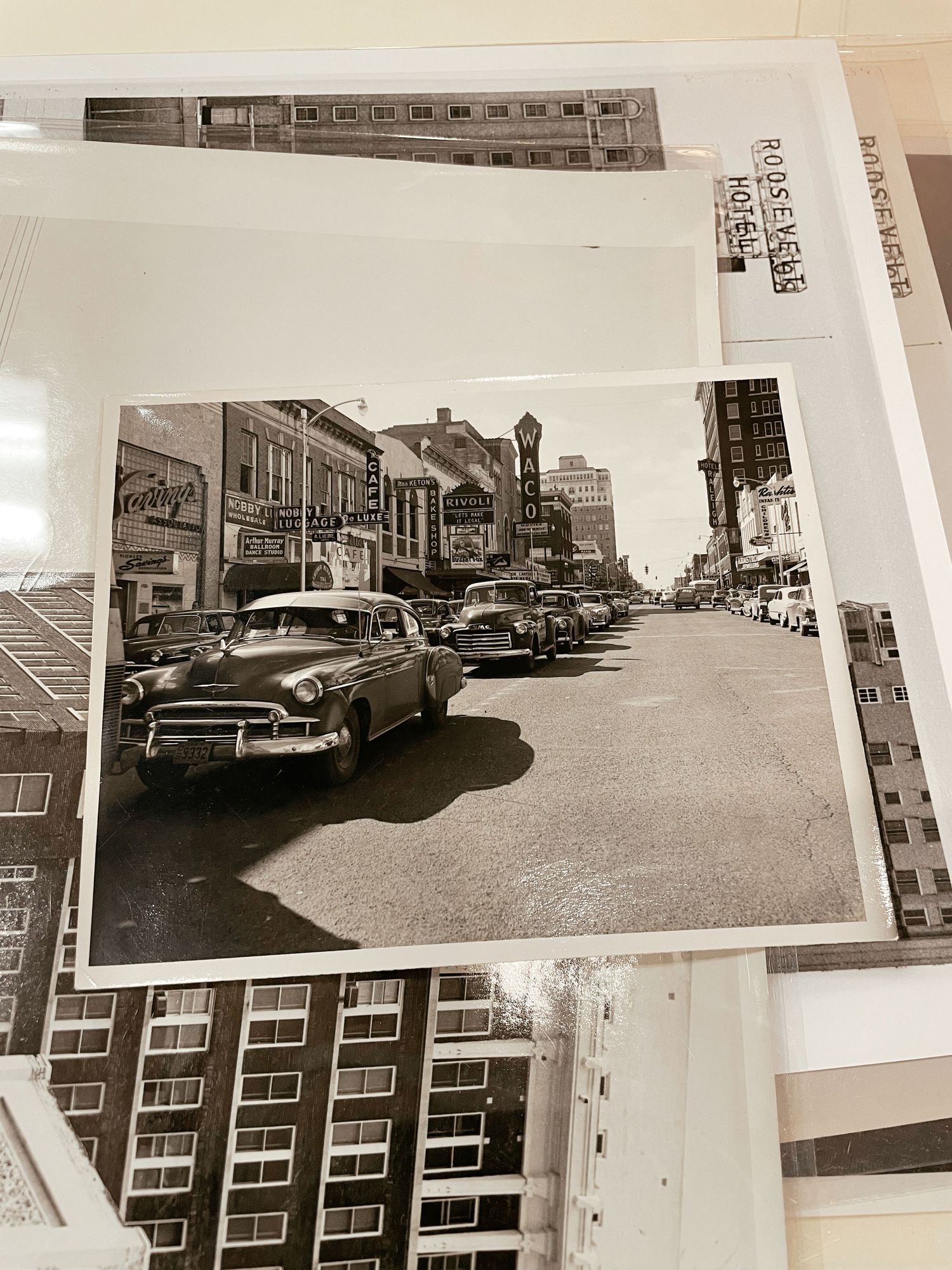Vintage black and white photo of a busy 1950s city street with classic cars and Roosevelt Hotel sign.