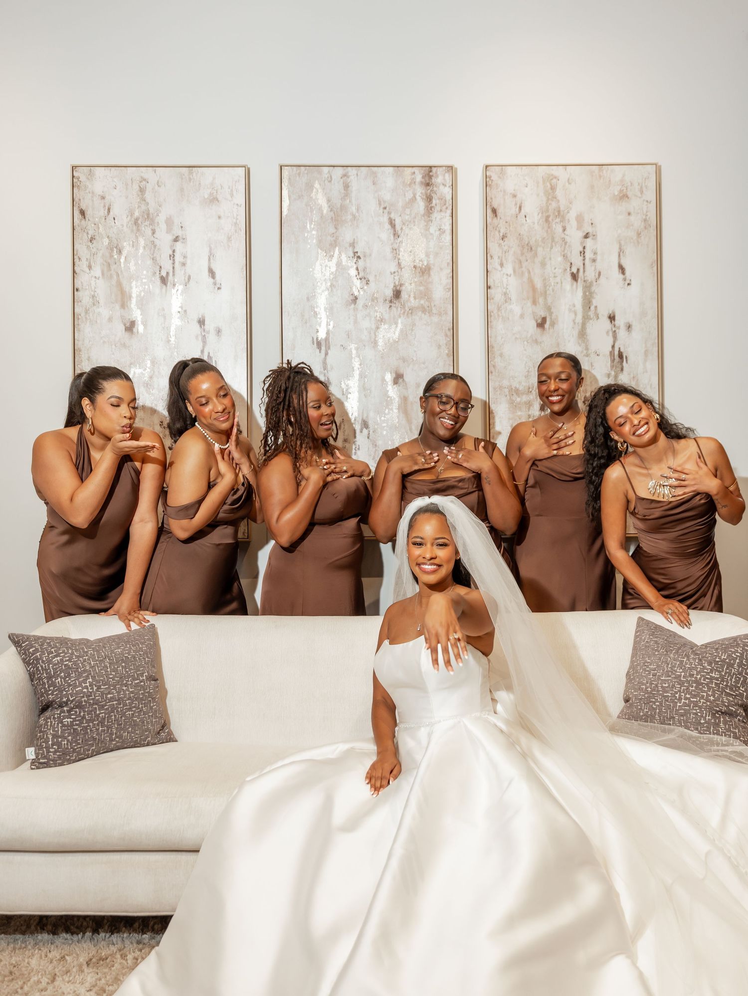 Tamara poses in her wedding dress with bridesmaids seated behind her.