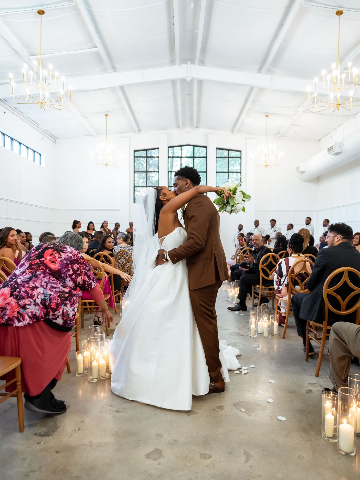 Makhi and Tamara embrace during their wedding ceremony, surrounded by guests.