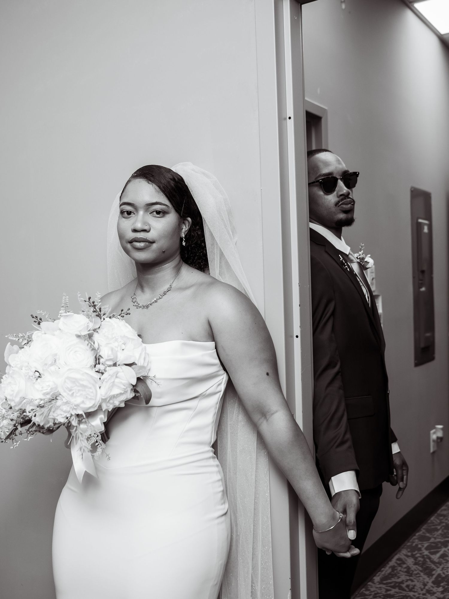 Black-and-white wedding portrait of the bride and groom on opposite sides of a doorway.