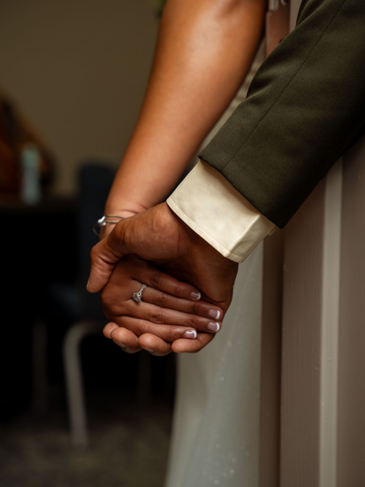 Close-up wedding photograph of Kayela and Isaac holding hands.