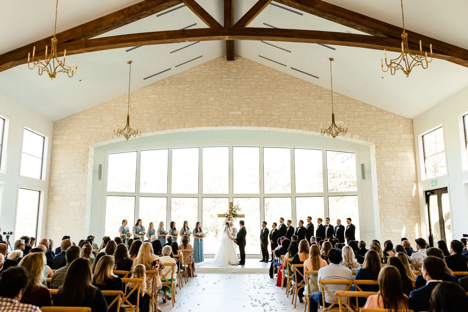 Wedding ceremony in a bright chapel with vaulted ceilings and large windows.