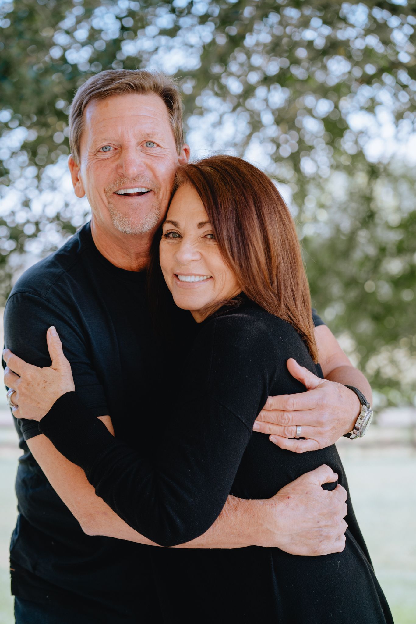 Happy mature couple embracing and smiling together outdoors in a lush green park setting.