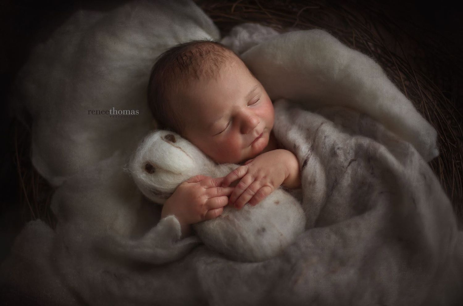 Peaceful sleeping newborn baby cuddling a soft white stuffed animal on a cozy fur blanket.