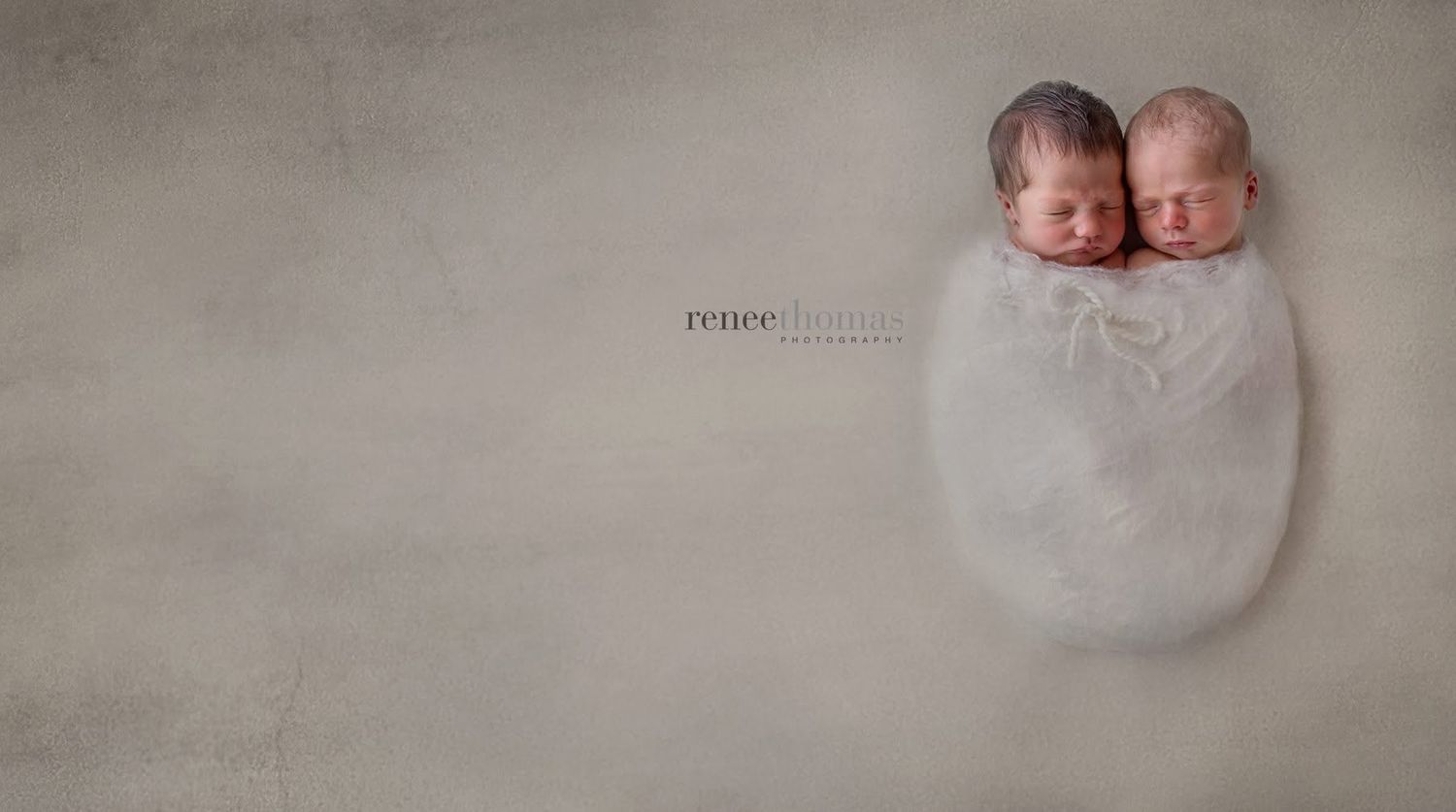 Two swaddled newborn twins wrapped together in white cloth on neutral background.