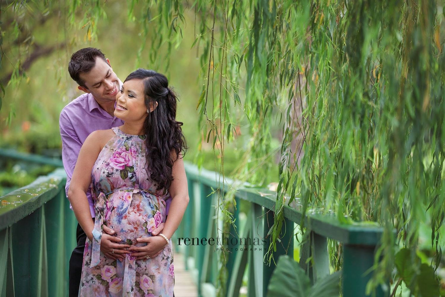 Expecting couple embracing tenderly under weeping willow tree in a maternity portrait by Renee Thomas.