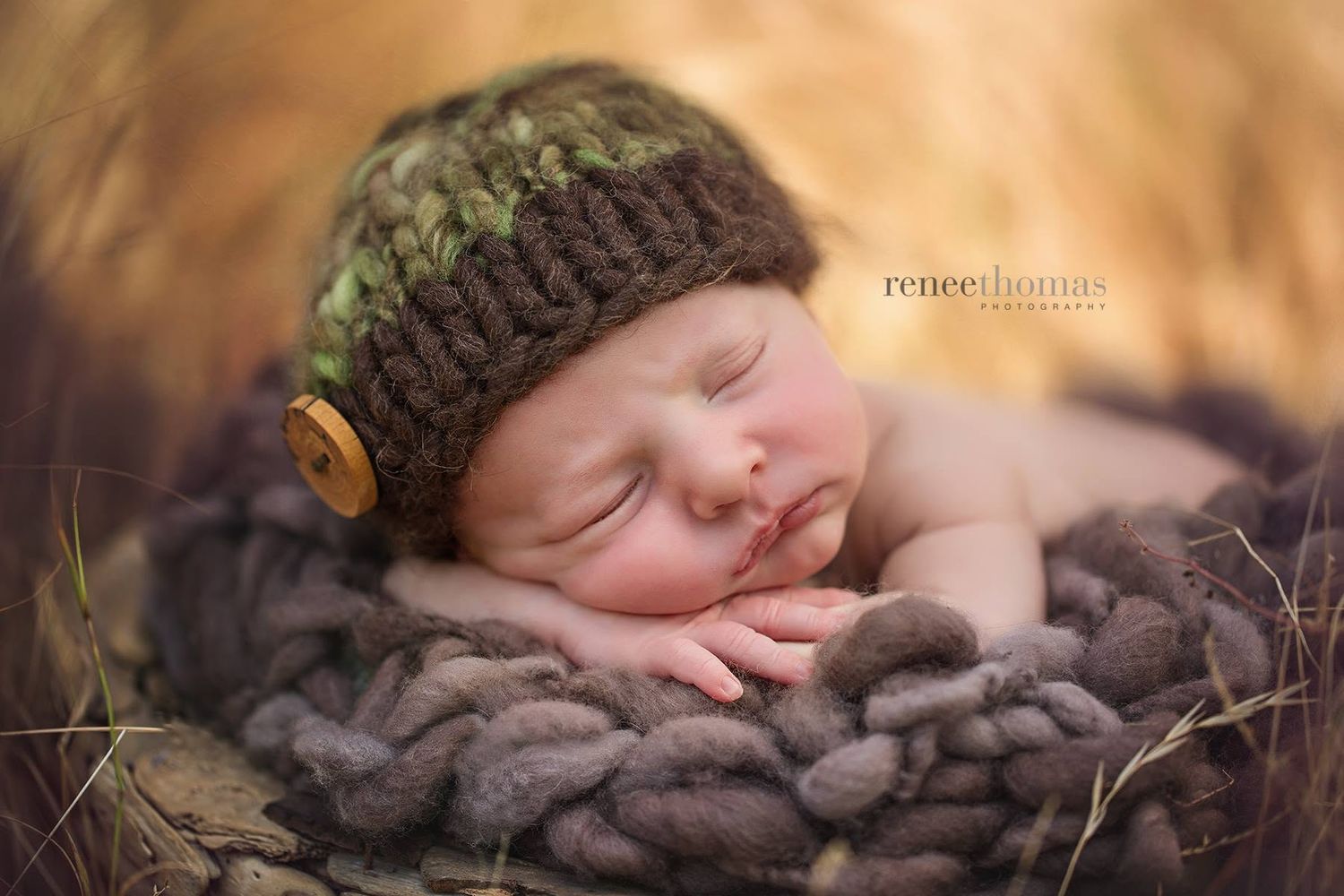 Sleeping newborn baby wearing a knit camo hat nestled in a cozy bowl by Renee Thomas Photography.