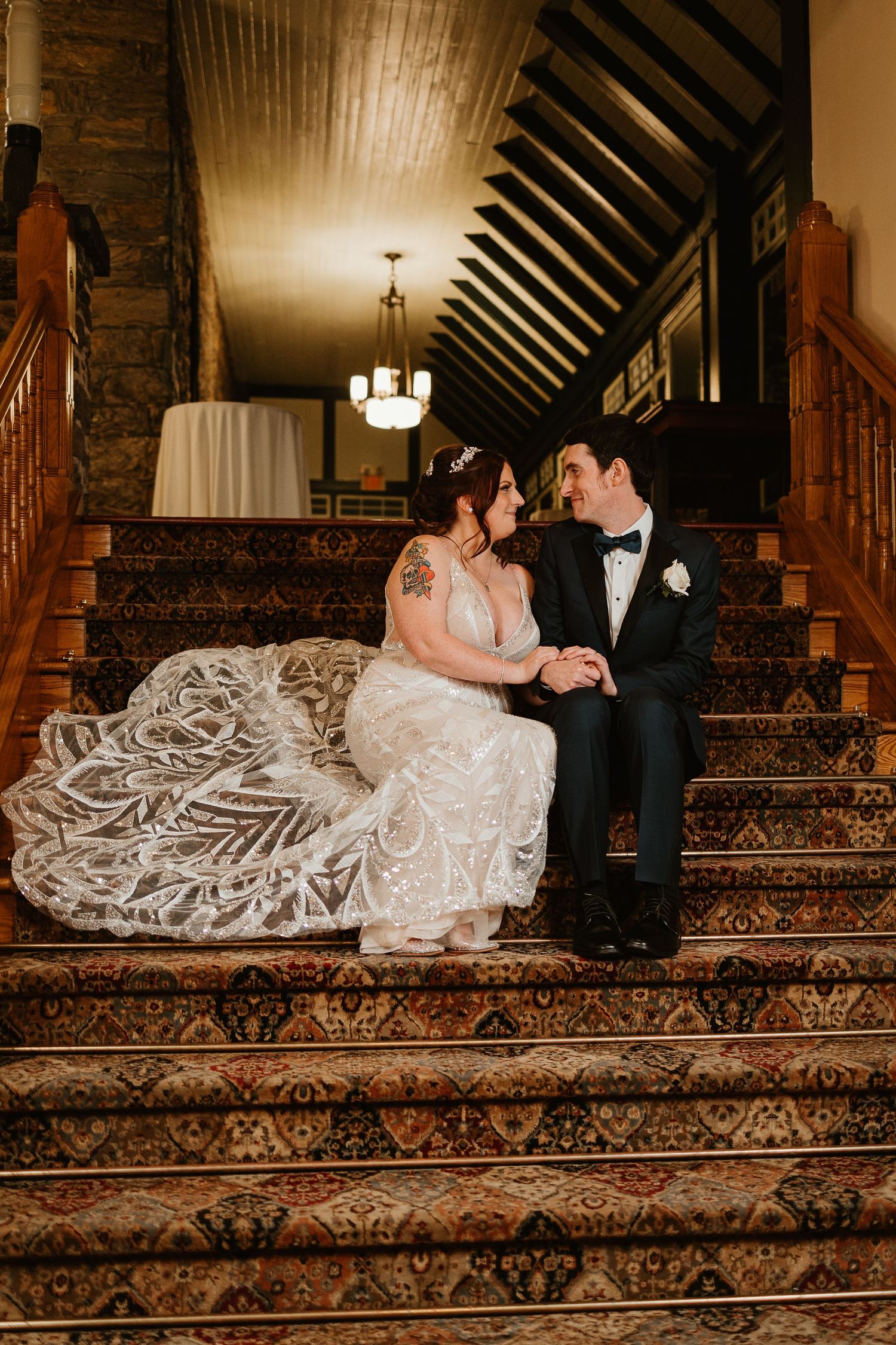 Newlyweds share an intimate moment on elegant carpeted stairs in a vintage venue.