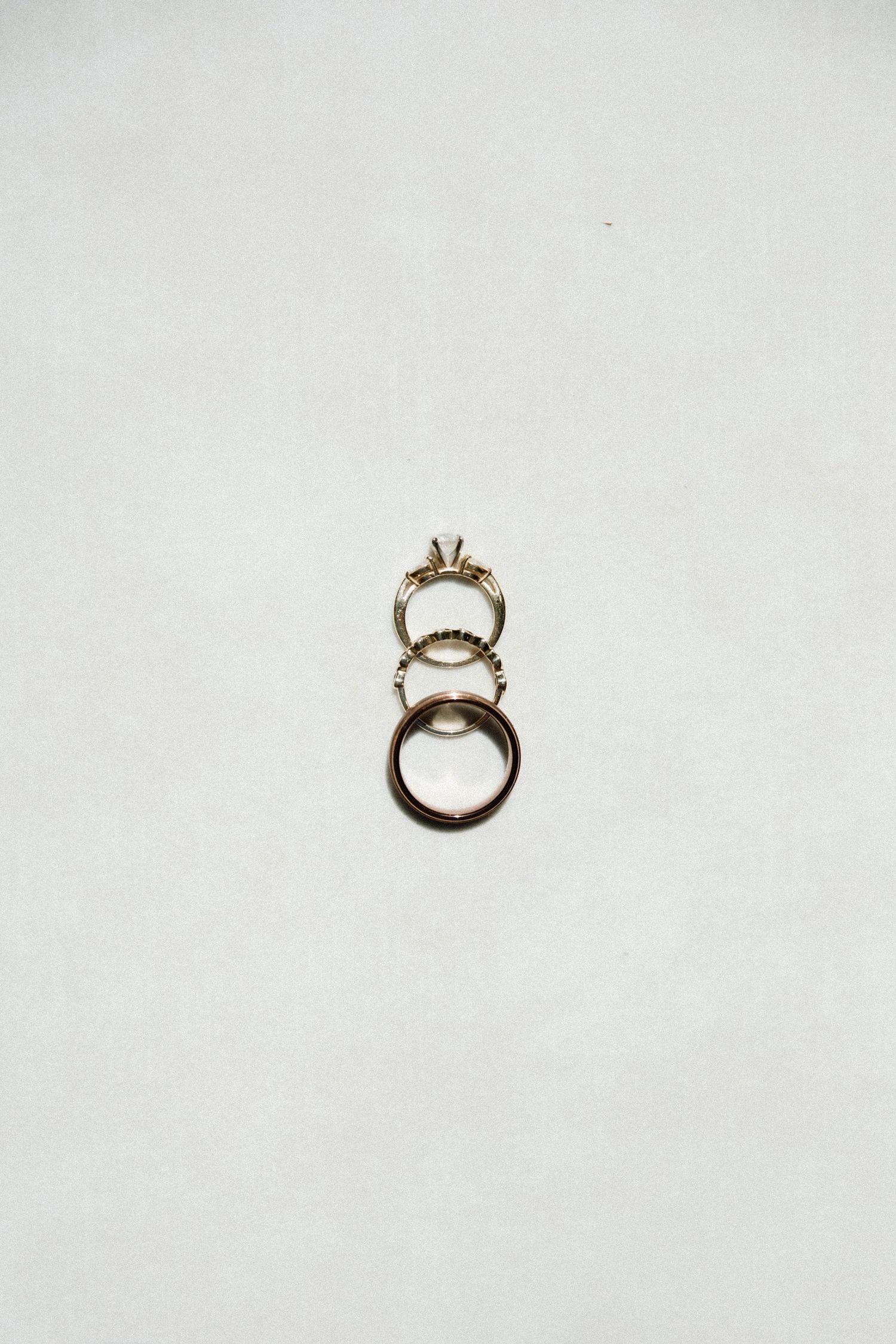 Three elegant wedding rings arranged vertically on a white background.