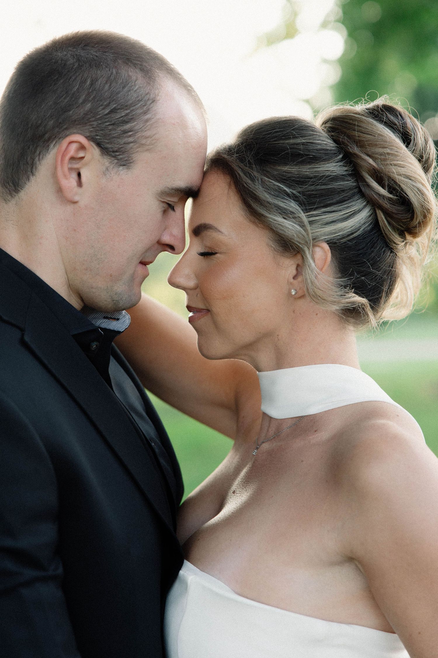 Intimate romantic wedding portrait session captures couple in natural sunlight with soft focus.