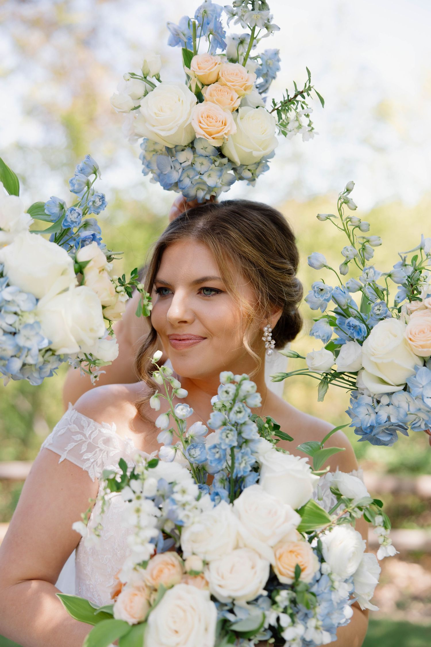 Beautiful floral arrangement with peach roses, white flowers and blue delphinium in a romantic outdoor garden setting.
