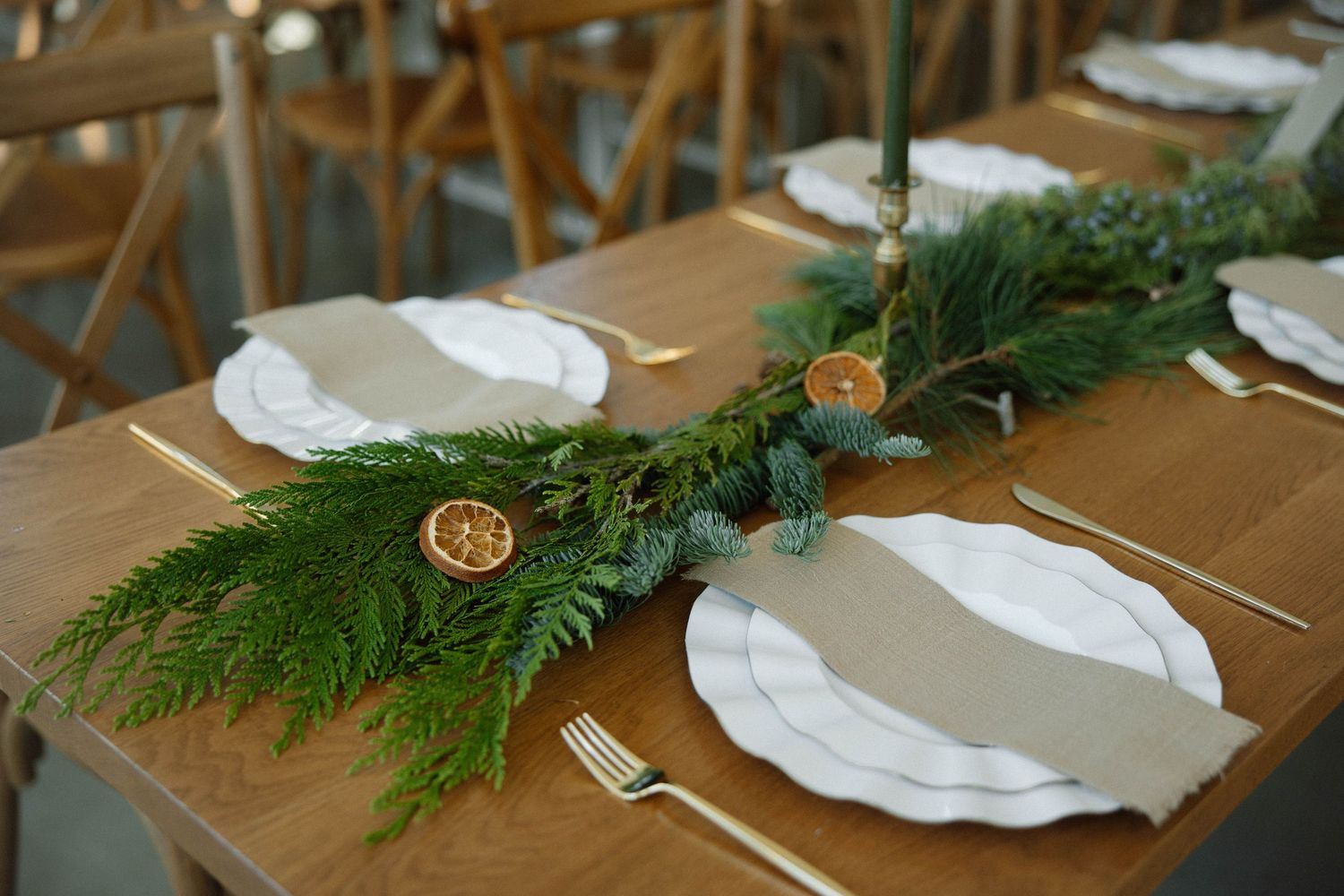 Elegant table setting with fresh greenery garland and white plates for wedding reception.