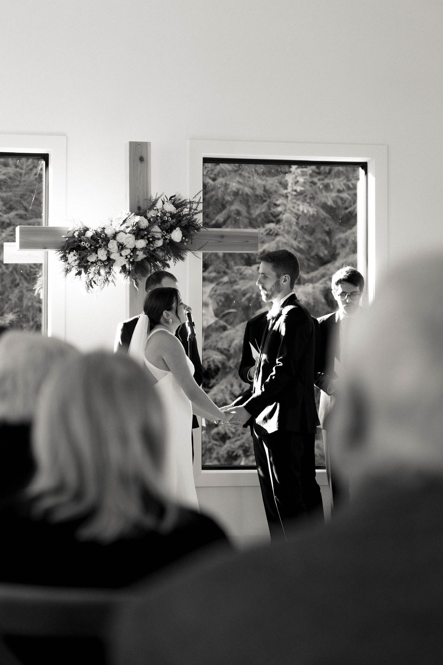 Black and white wedding ceremony photo showing couple at altar with floral decorations.