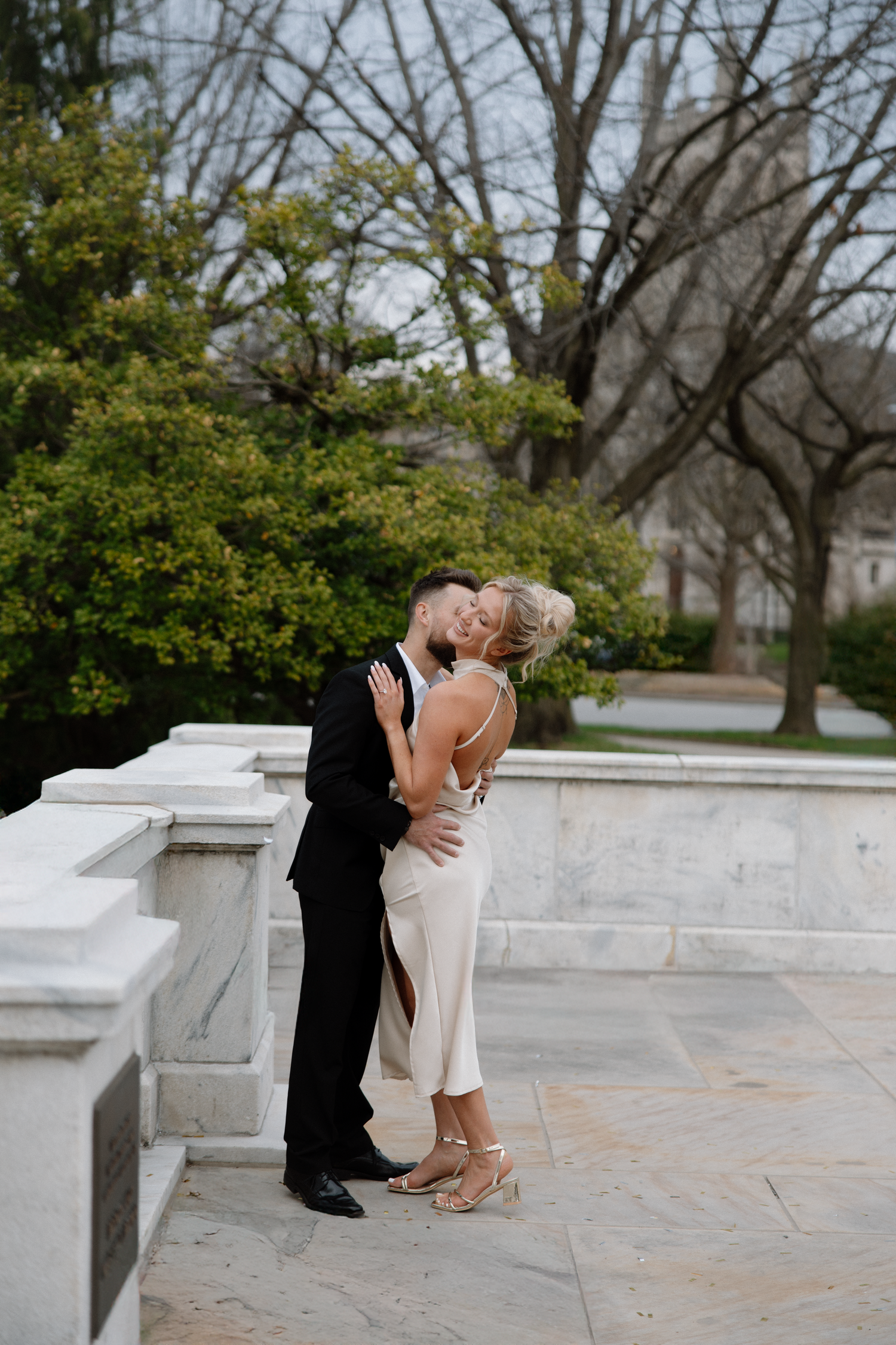 Romantic moment captured between couple in formal wear on stone terrace with trees in background. Cleveland, OH
