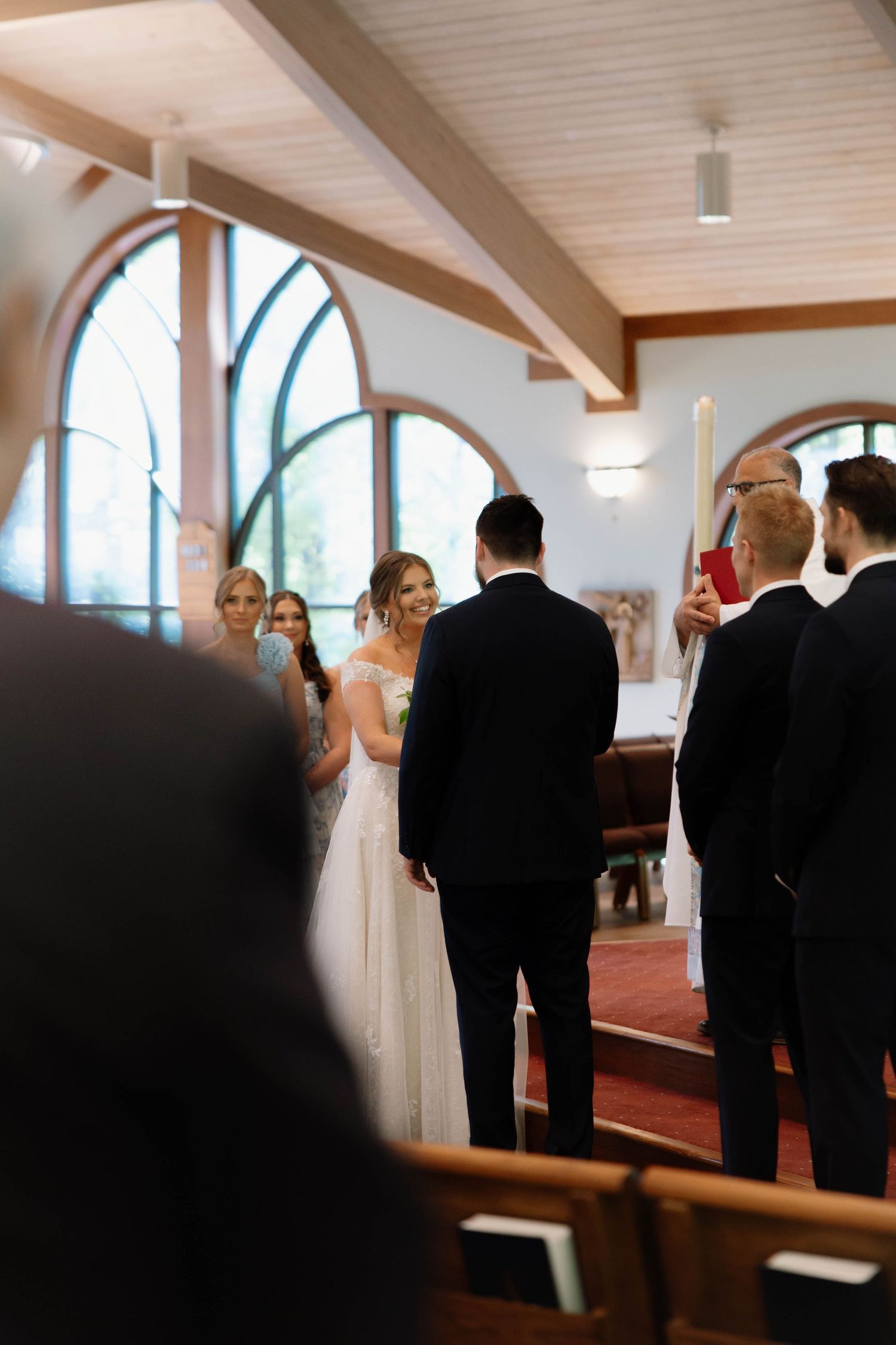 A wedding ceremony taking place in a church with arched windows and cathedral ceilings.