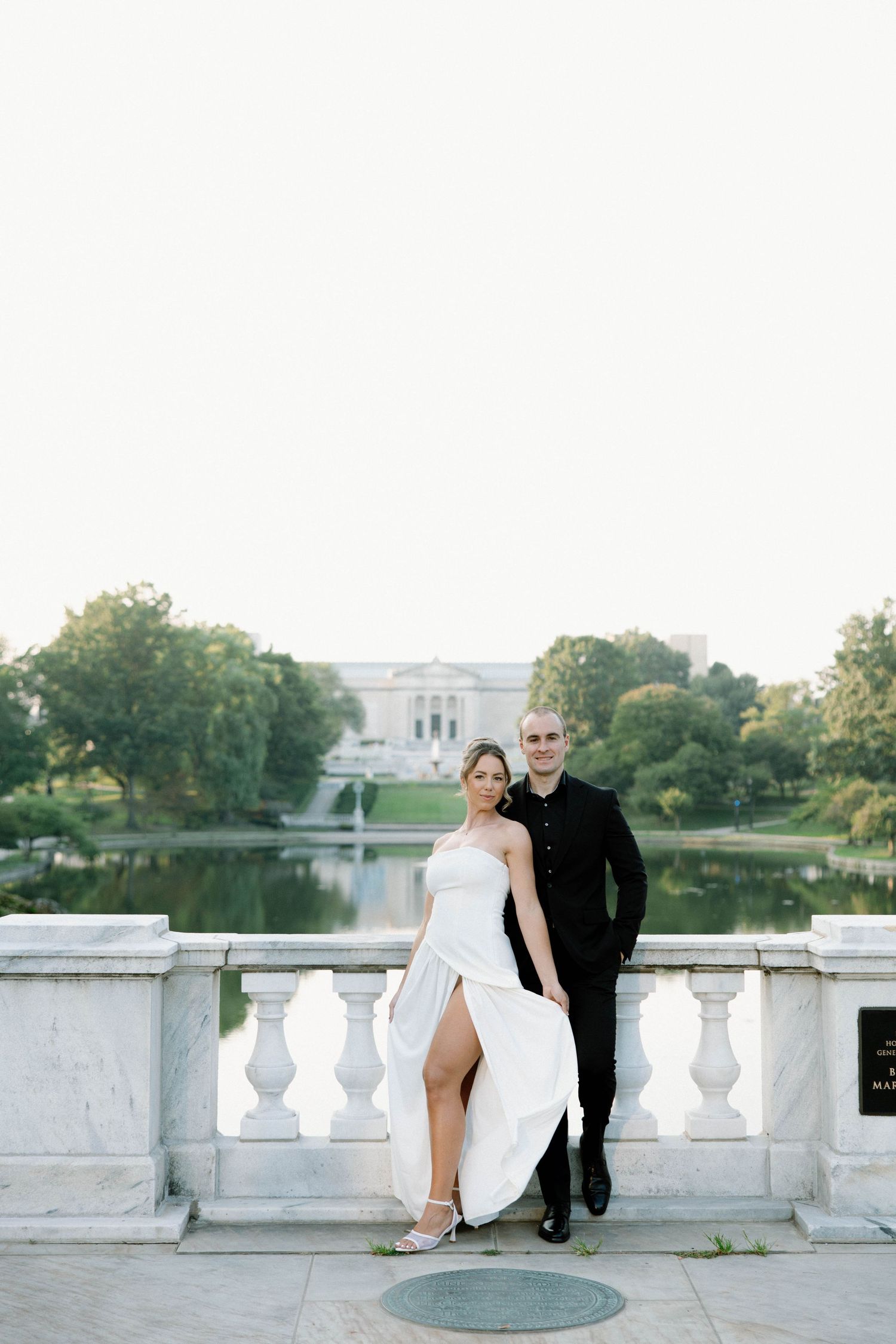 A romantic wedding photo session at a grand stone balustrade with a fountain and building in the background.