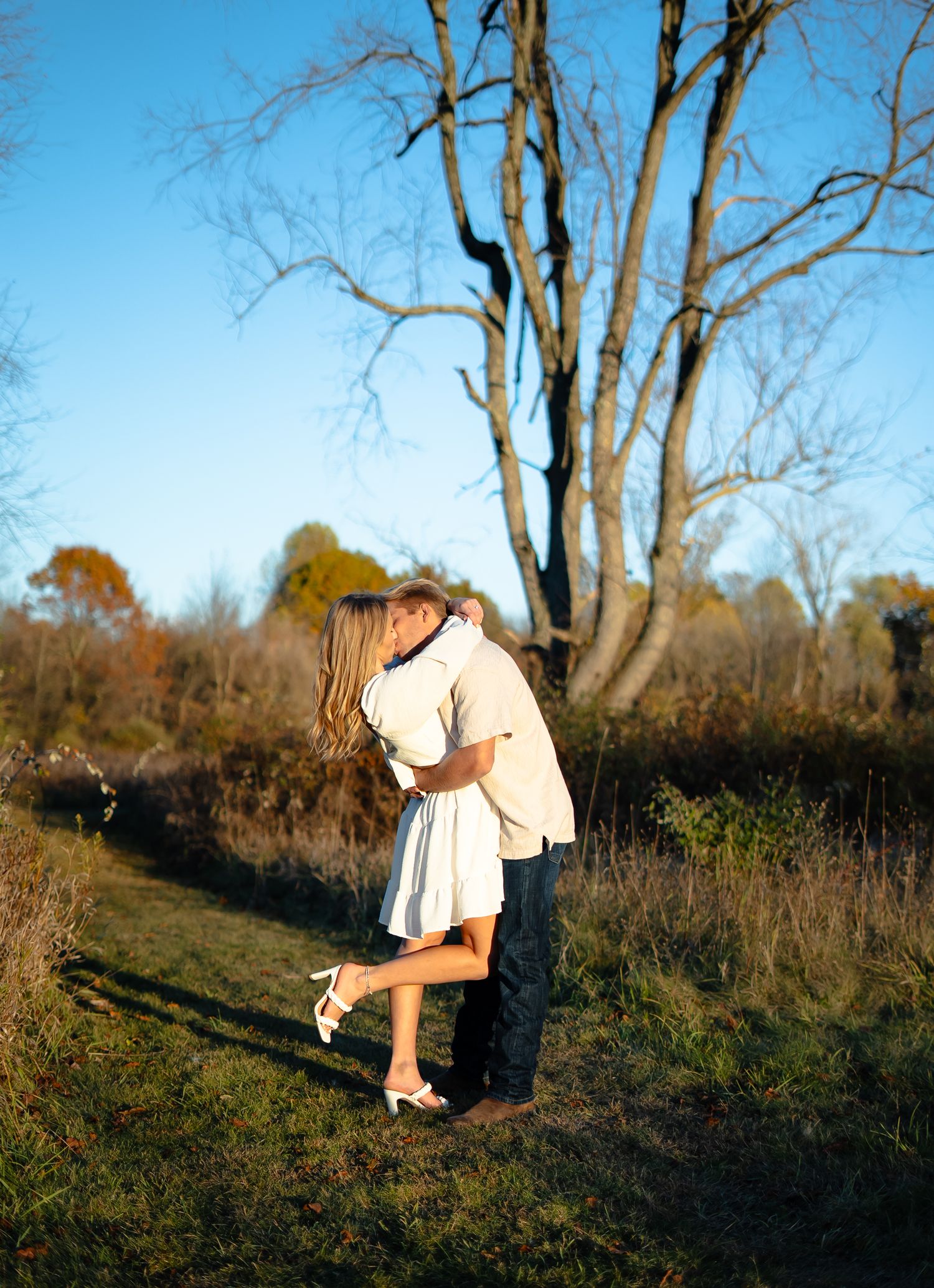 A romantic outdoor photoshoot in a golden field at sunset with soft natural lighting and long shadows.