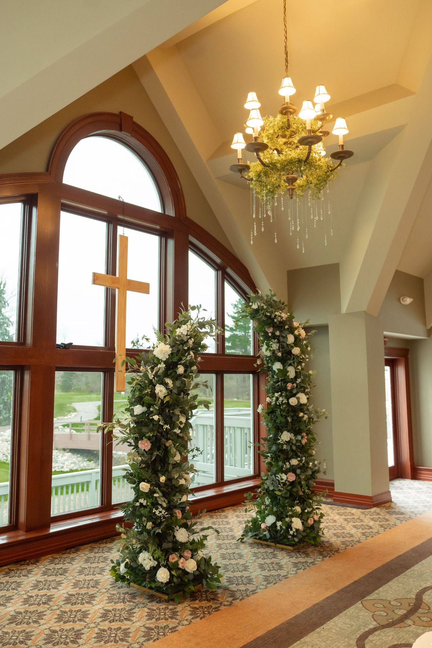 An elegant chapel interior with floral arches, wooden cross and chandelier.
