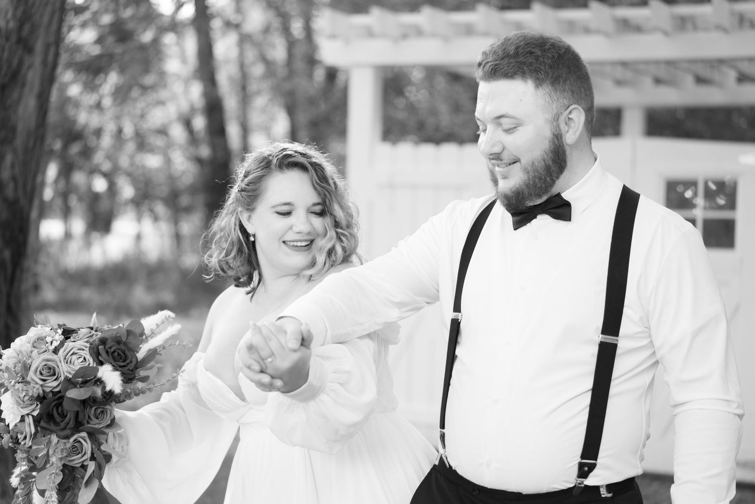 A joyful wedding couple shares a playful moment in black and white photography.