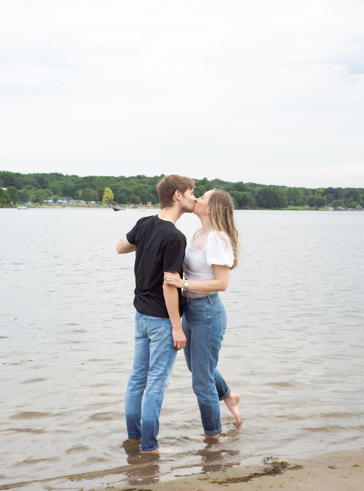 Couple sharing an intimate moment while standing in shallow water at the lake's edge.