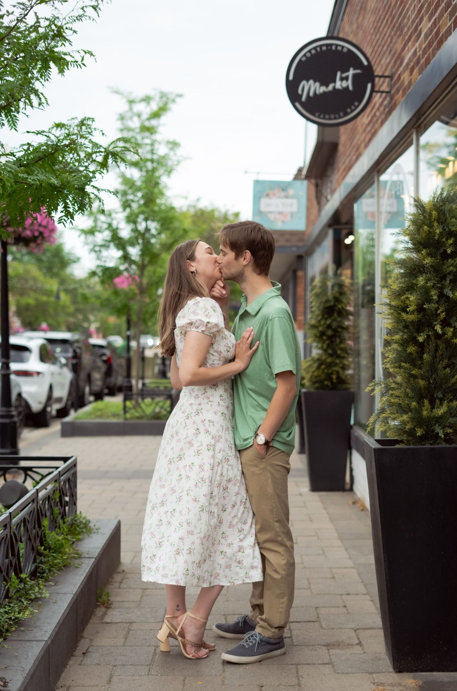 Romantic moment shared between couple outside a storefront with urban landscaping.