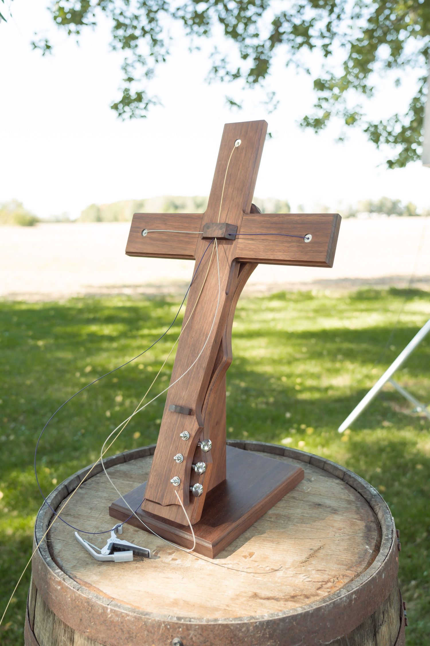 A wooden cross display on a rustic barrel in an outdoor setting.