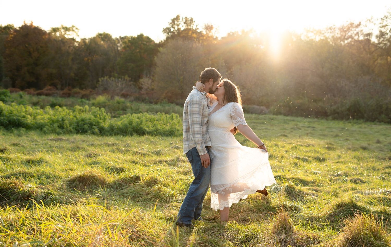 Couple dancing in a sunlit meadow during golden hour.