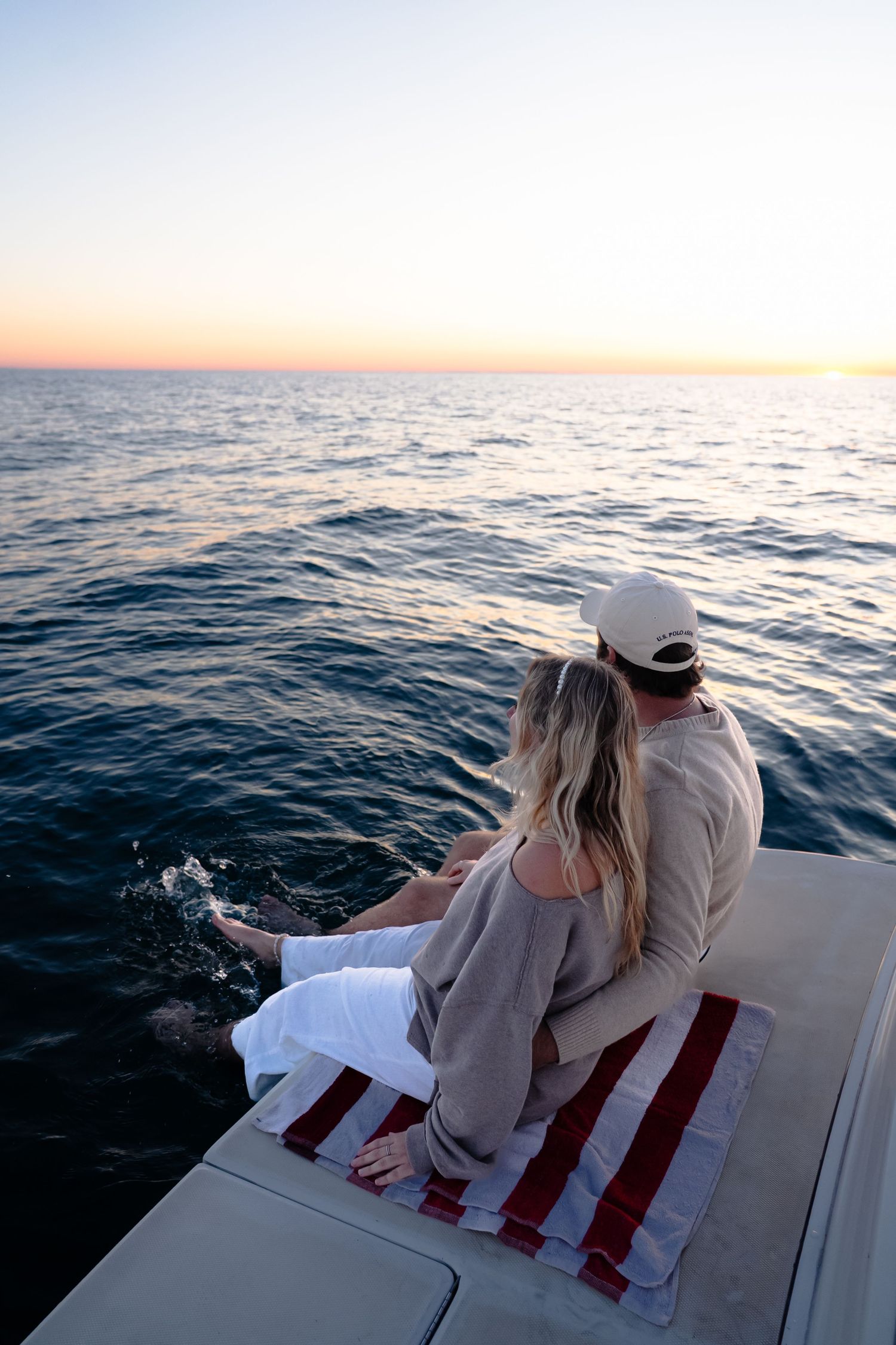 Two people relaxing on a boat deck at sunset across multiple snapshots with the ocean's blue waters in view.