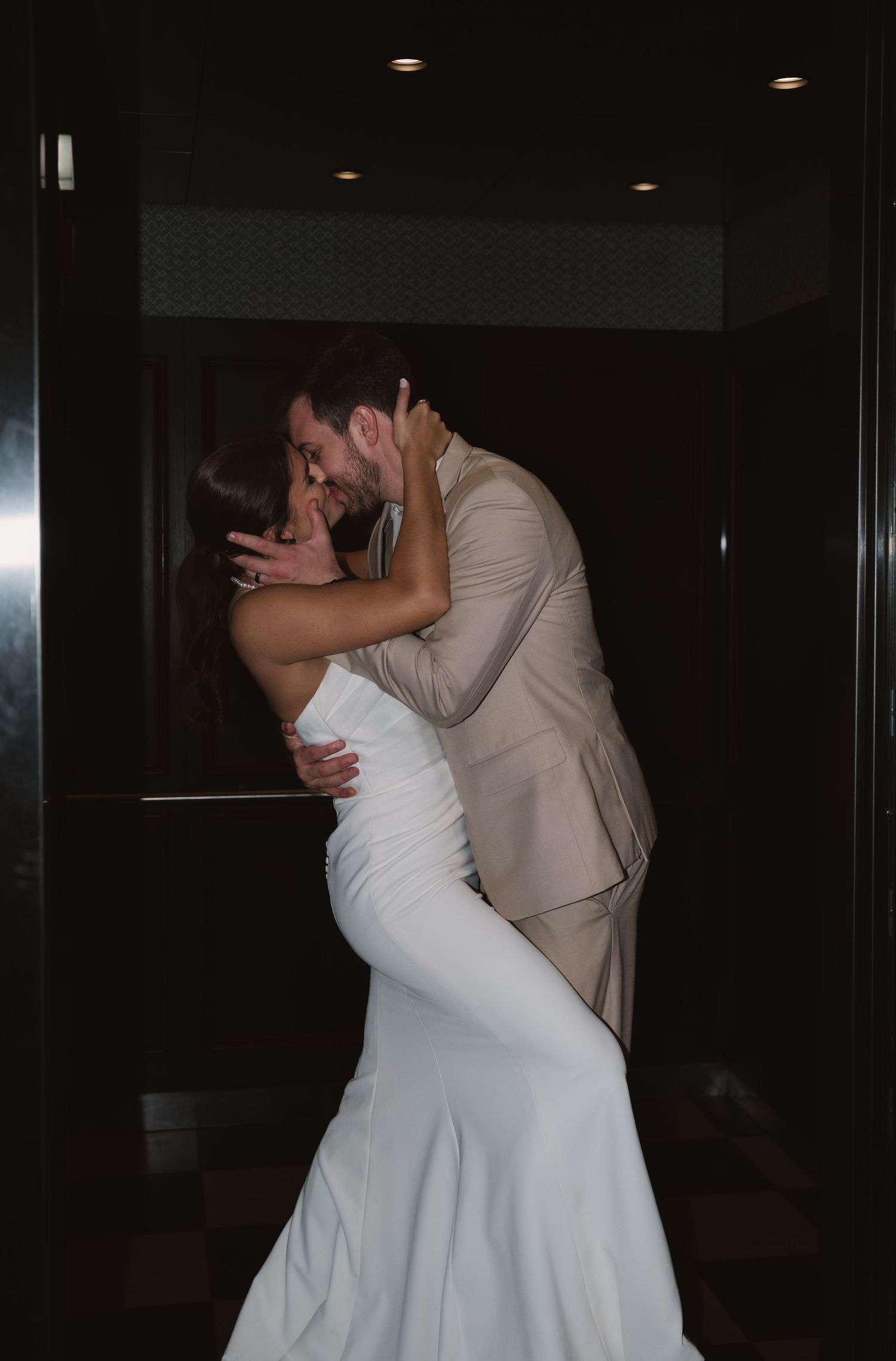 A romantic moment between newlyweds sharing their first kiss as a married couple in their wedding attire.