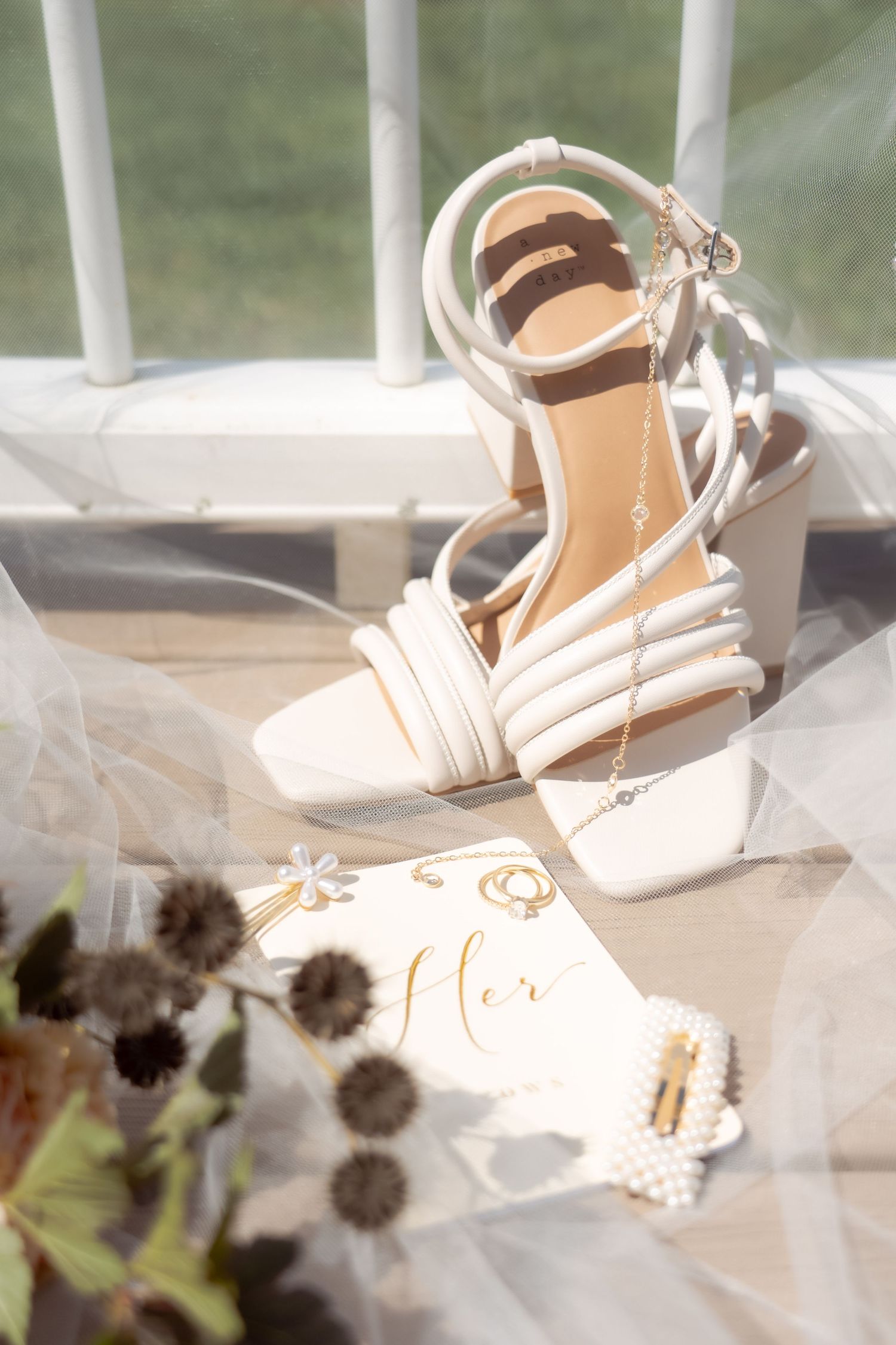 Elegant white bridal sandals with delicate straps displayed with veil and accessories.