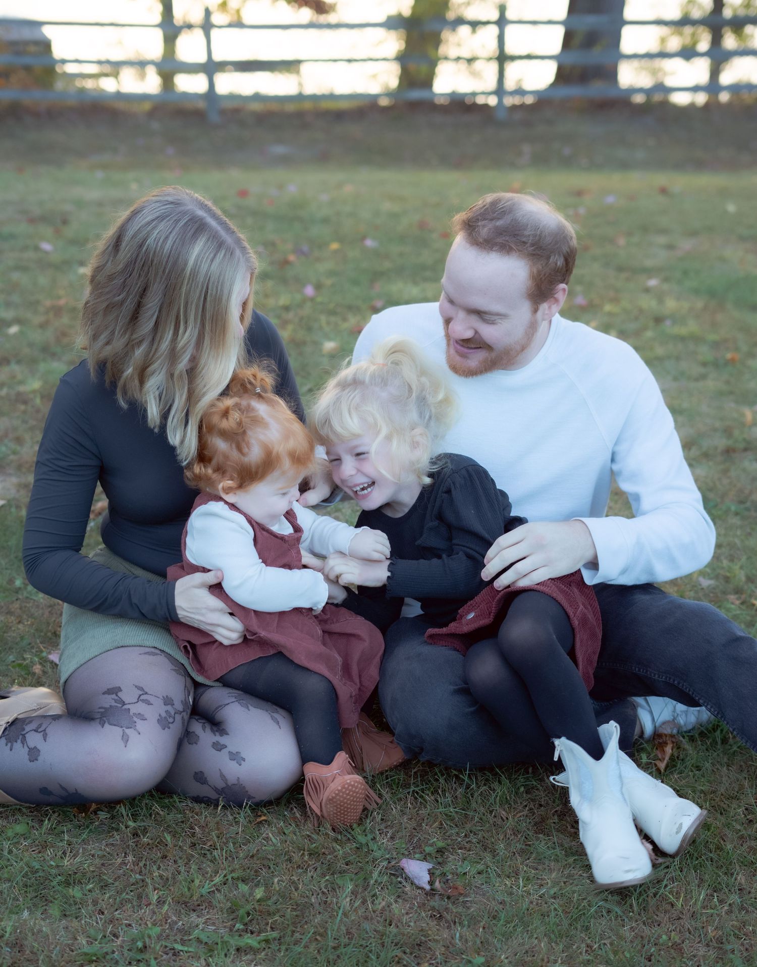 A candid family moment sitting together on grass during an autumn sunset.