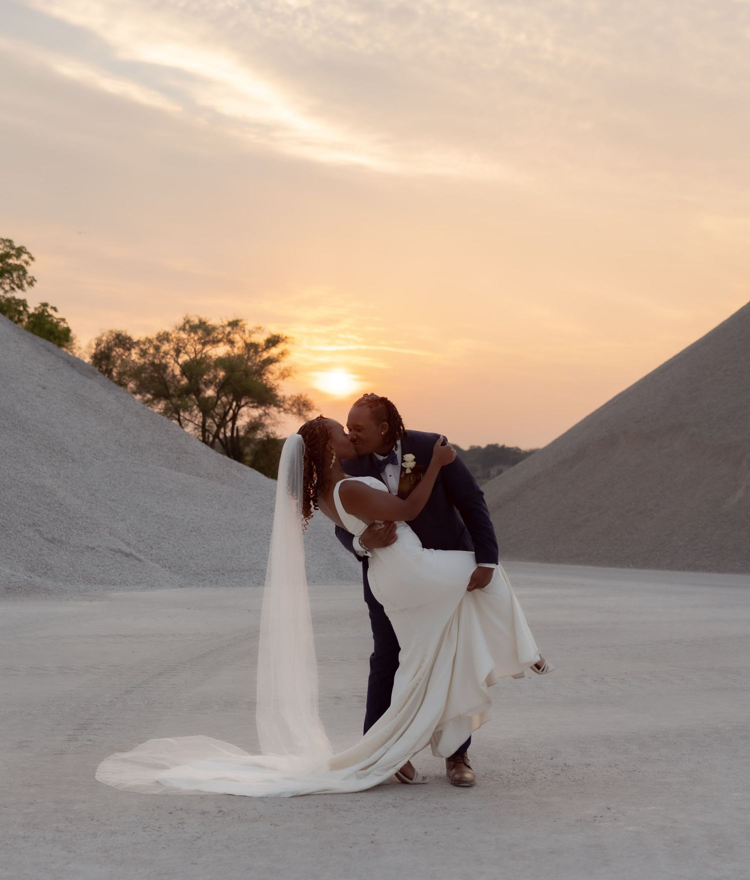 Romantic sunset wedding photo in quarry with flowing white dress and veil.