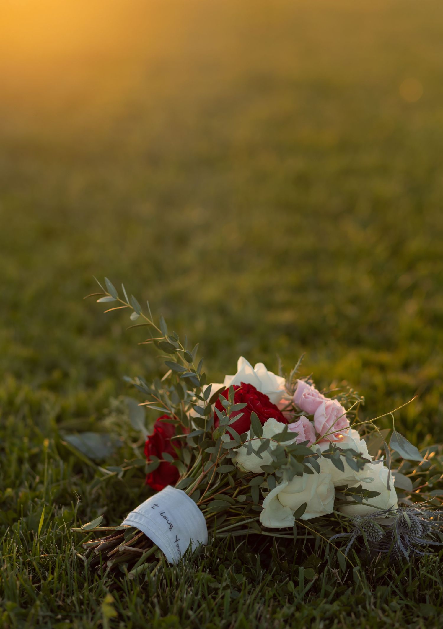 A floral arrangement rests on grass during golden hour sunset.