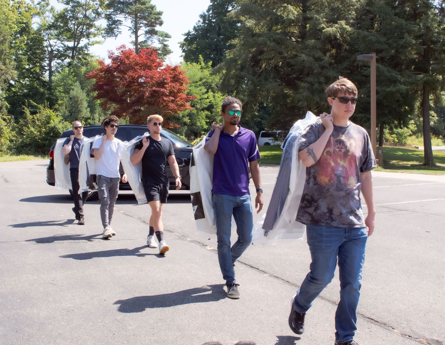 A group of people walking together outdoors on a sunny day with fall foliage and trees in the background.
