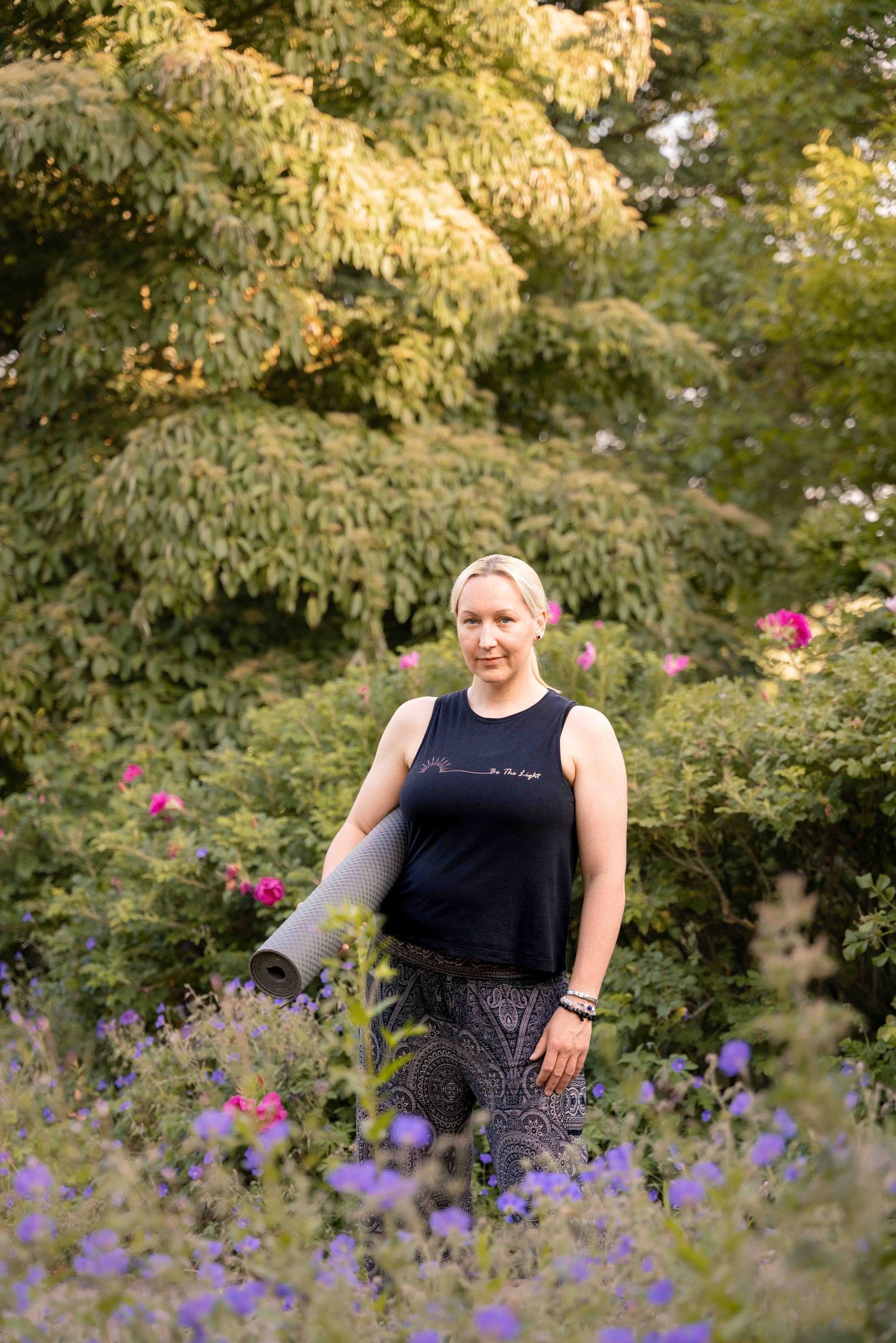 A figure stands among purple wildflowers in a garden with golden evening light. Lincolnshire branding photographer.