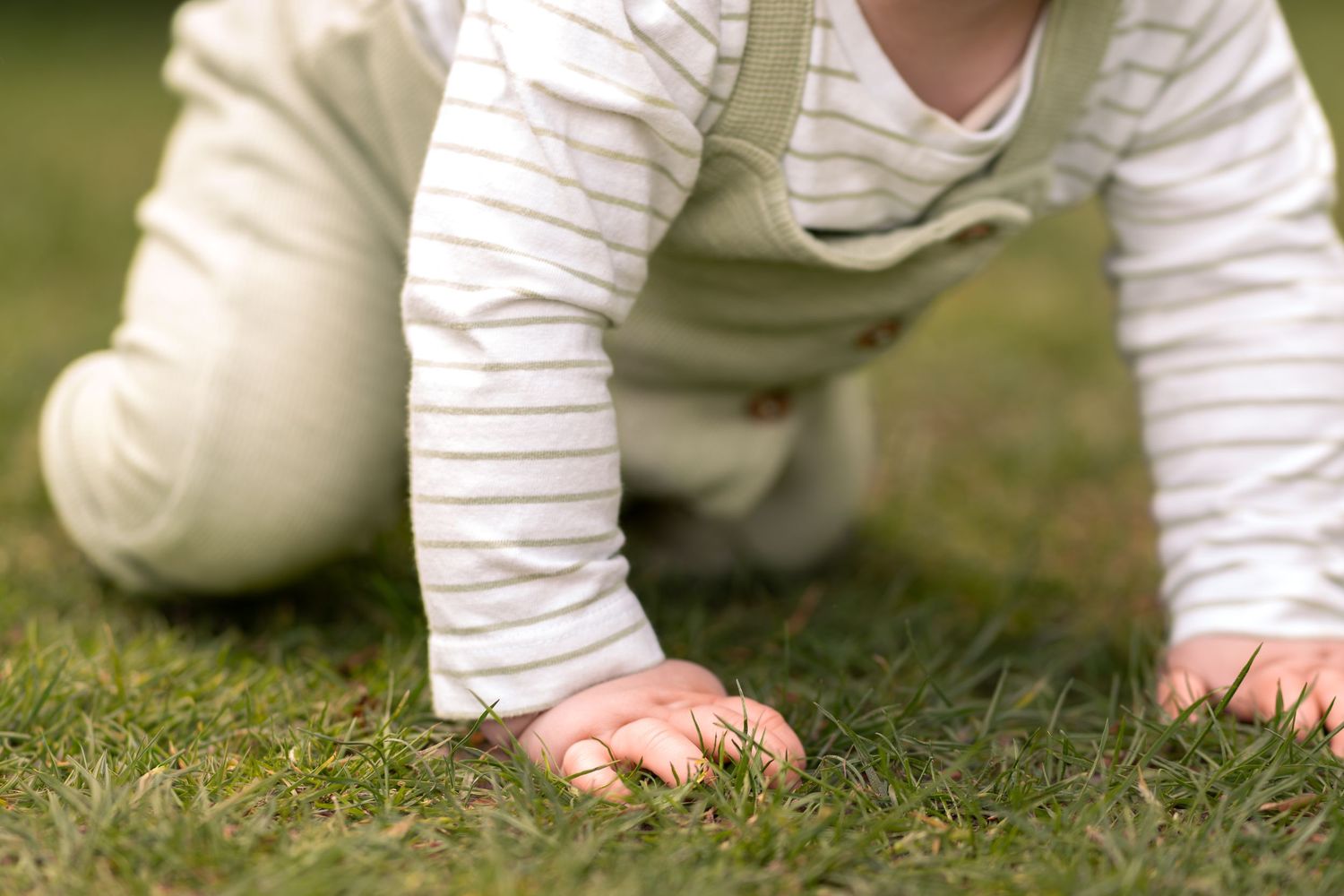 Baby crawling on green grass outdoors during a childhood photography session in Lincolnshire.