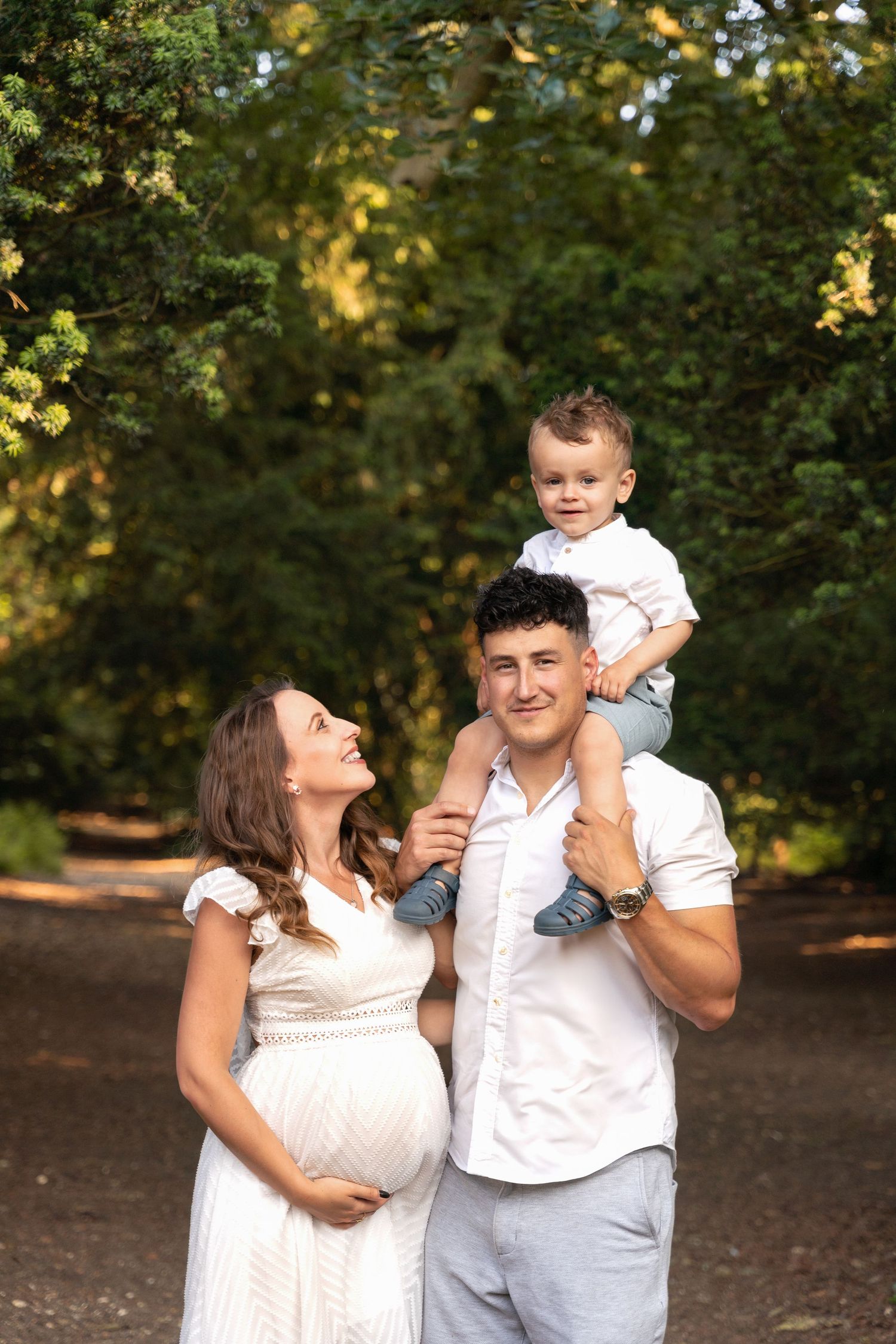 Family enjoying playful moments together in a park setting with autumn trees in the background.