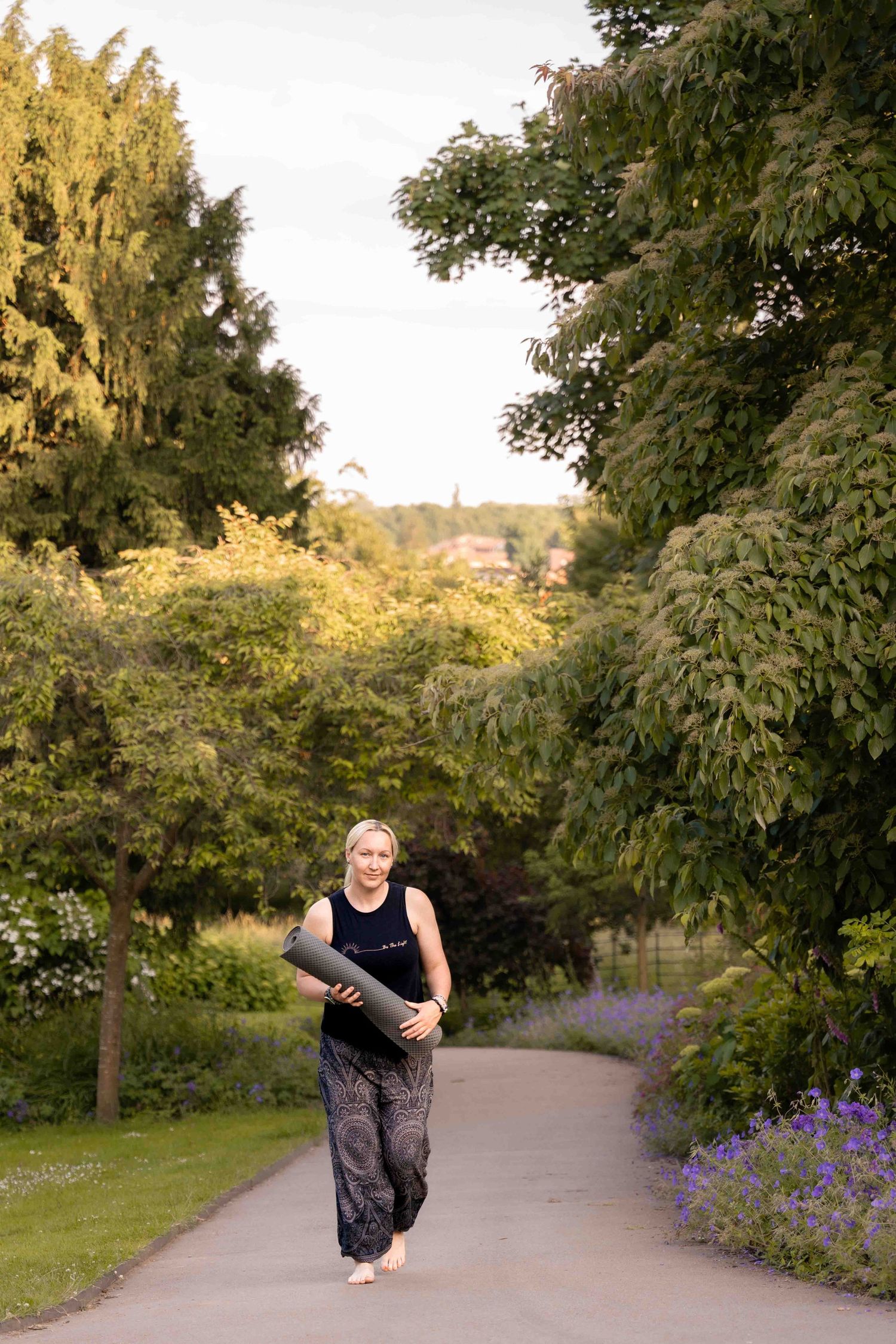 A person jogs along a garden path lined with purple flowers and lush trees. Lincolnshire branding photographer.