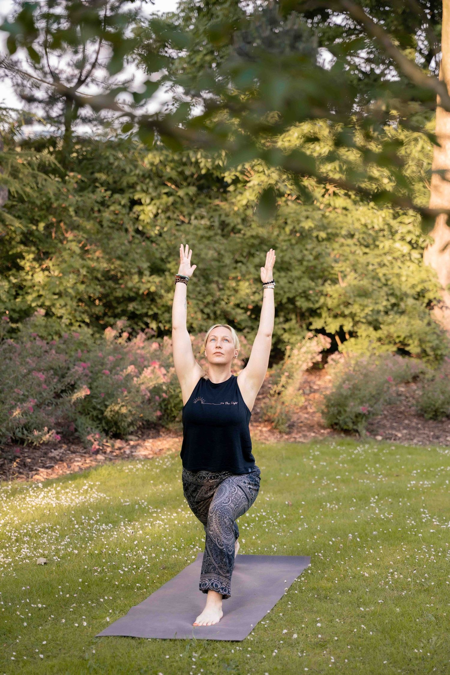 A person performs a yoga pose on a purple mat in a garden at sunset. Lincolnshire branding photographer.